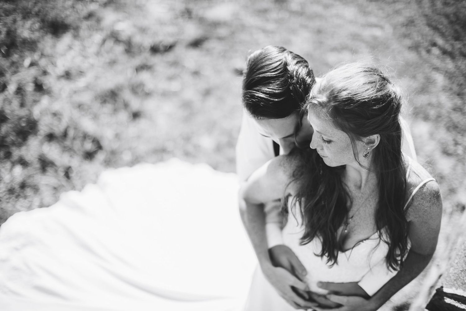 Black and white photo of a bride and groom sharing an intimate moment outdoors on their wedding day.