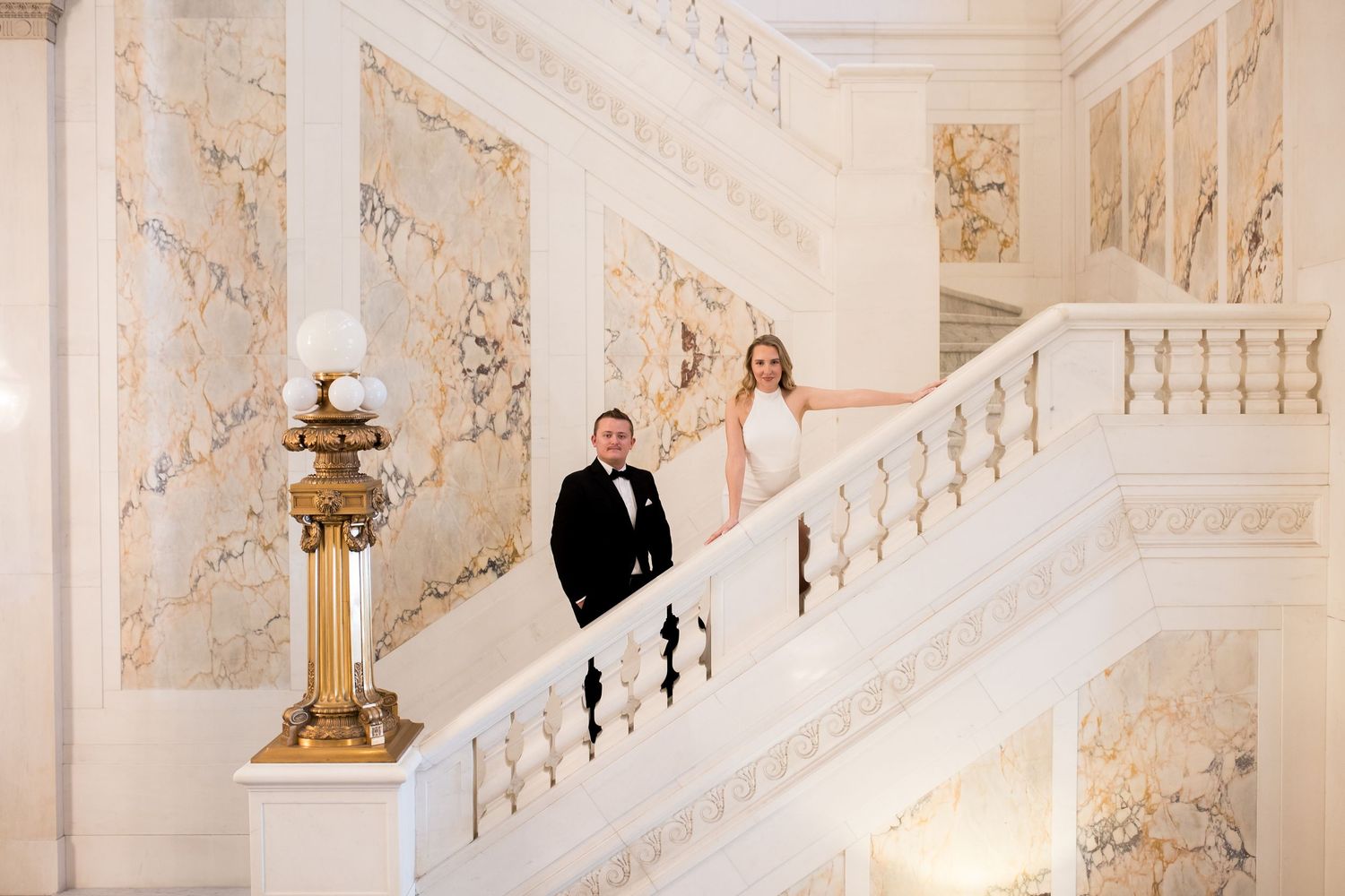Bride and groom posing on the elegant white marble staircase at The Belvedere Hotel in Baltimore, MD.