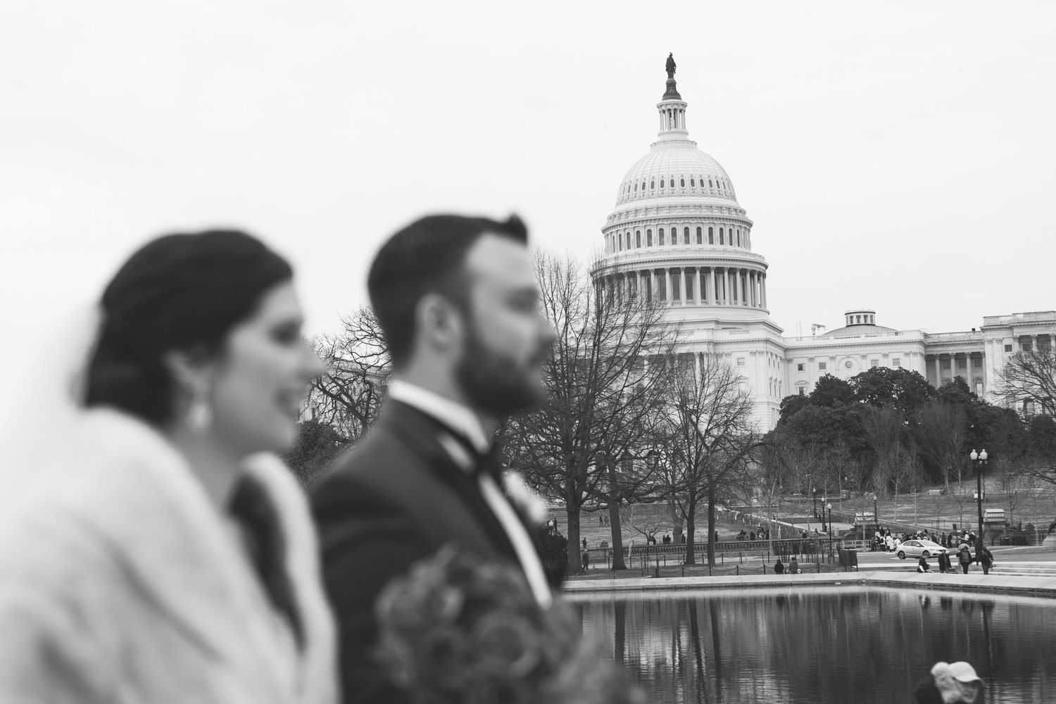 Black and white wedding photo of bride and groom with US Capitol building reflecting pool in Washington DC.