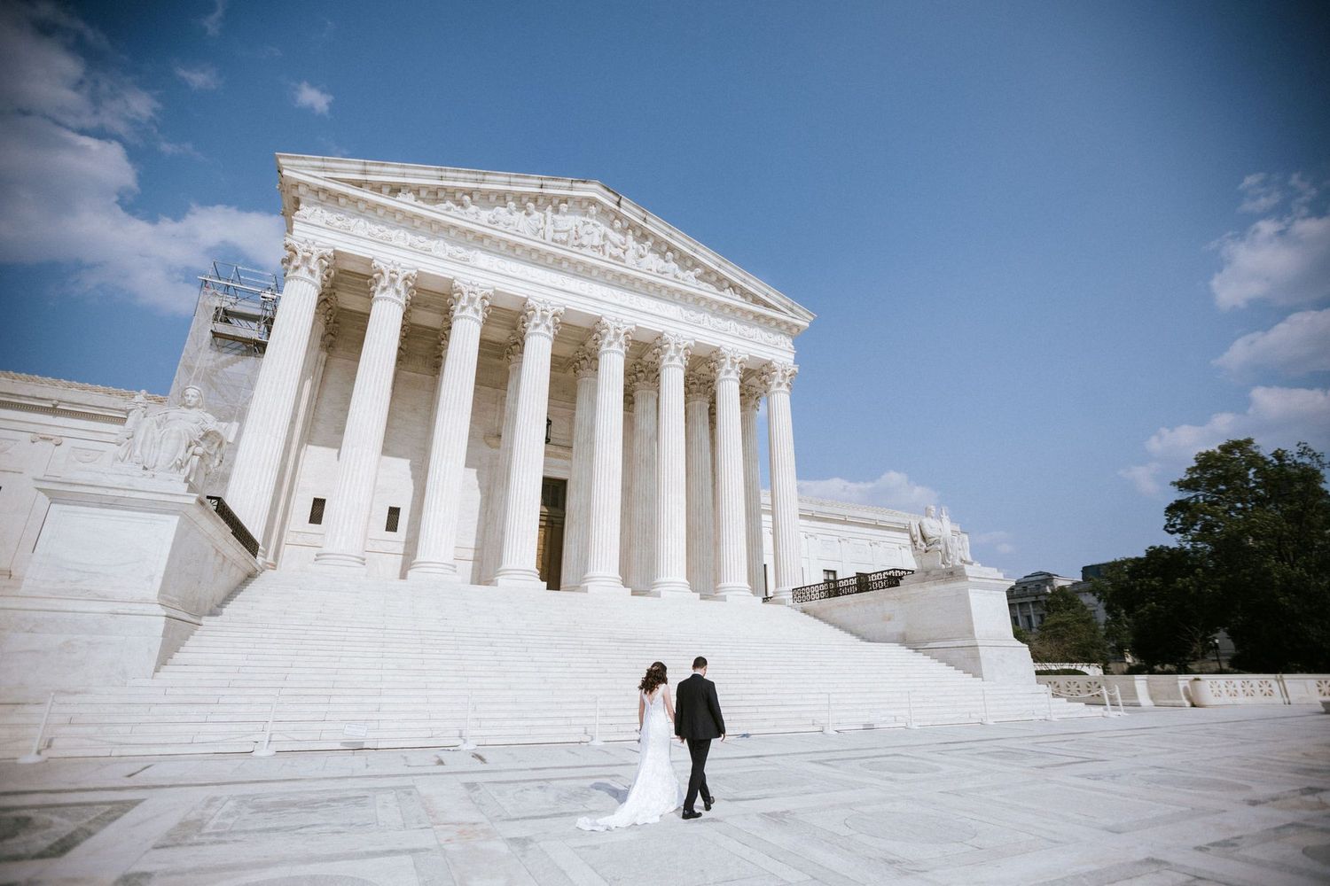 Bride and groom stand on steps of US Supreme Court building in Washington DC on their wedding day.
