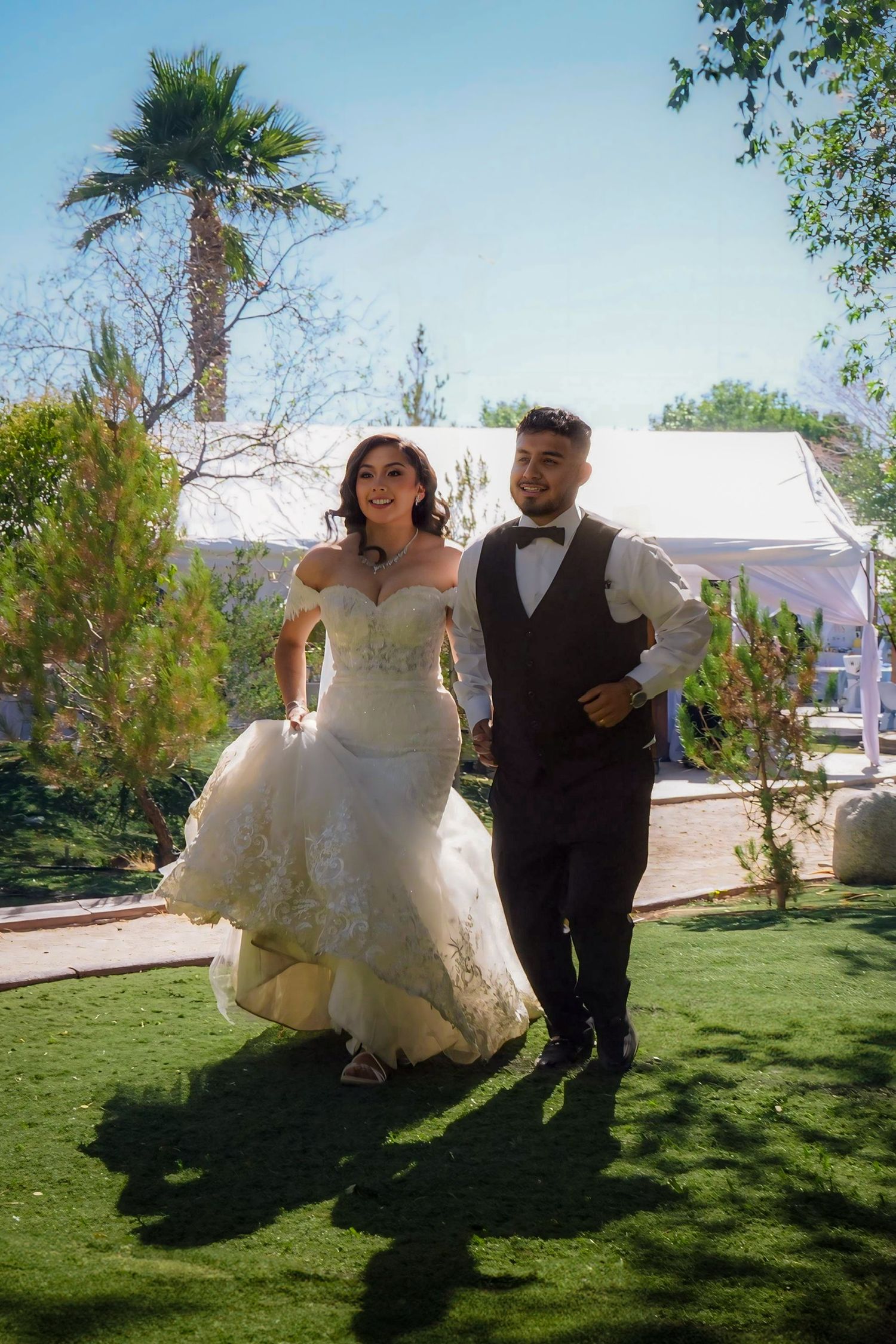 Newlywed couple playfully running away together hand in hand from their wedding reception.