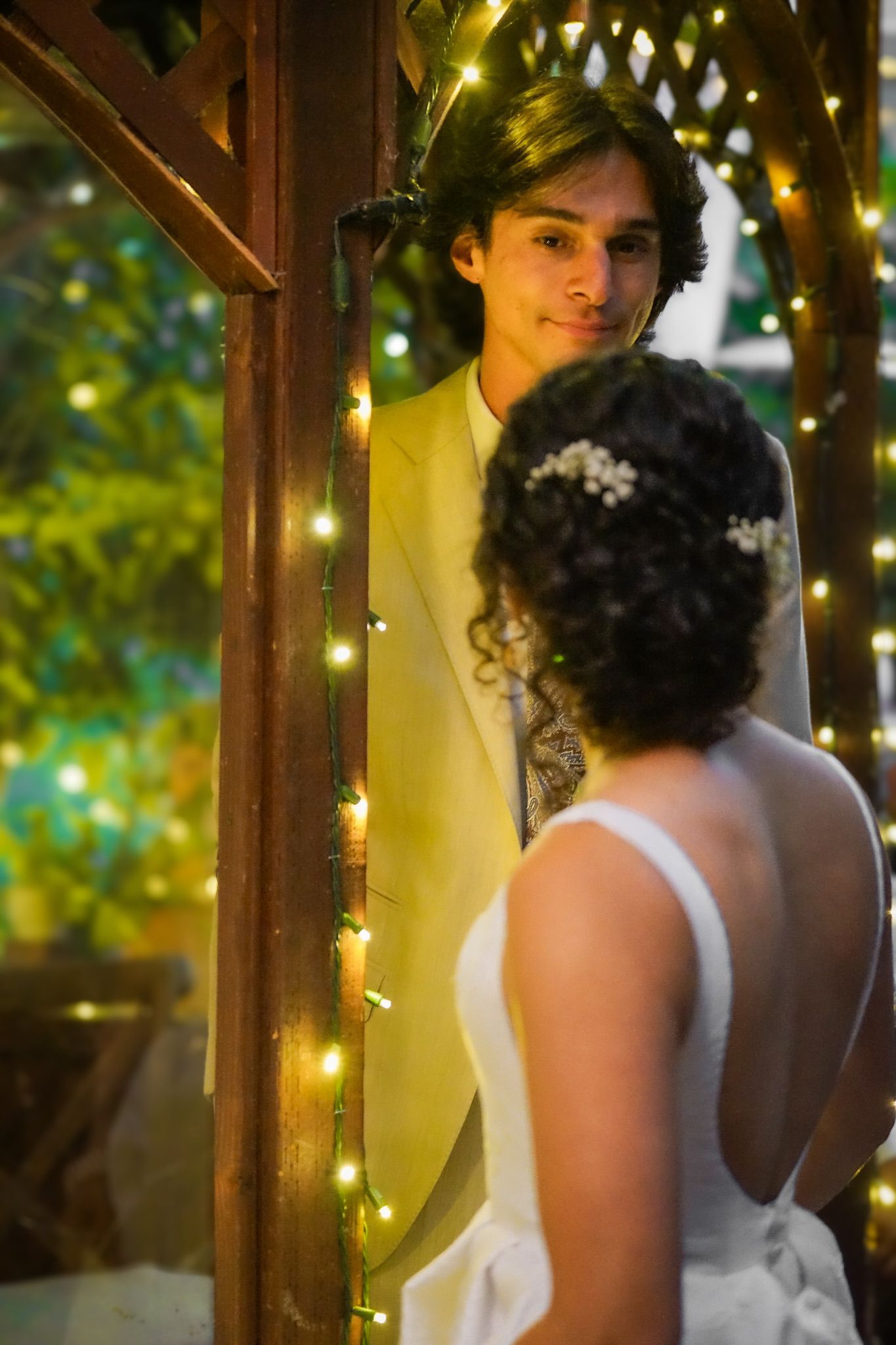Newlywed groom gazing lovingly at his bride from behind her, capturing a candid and romantic moment.