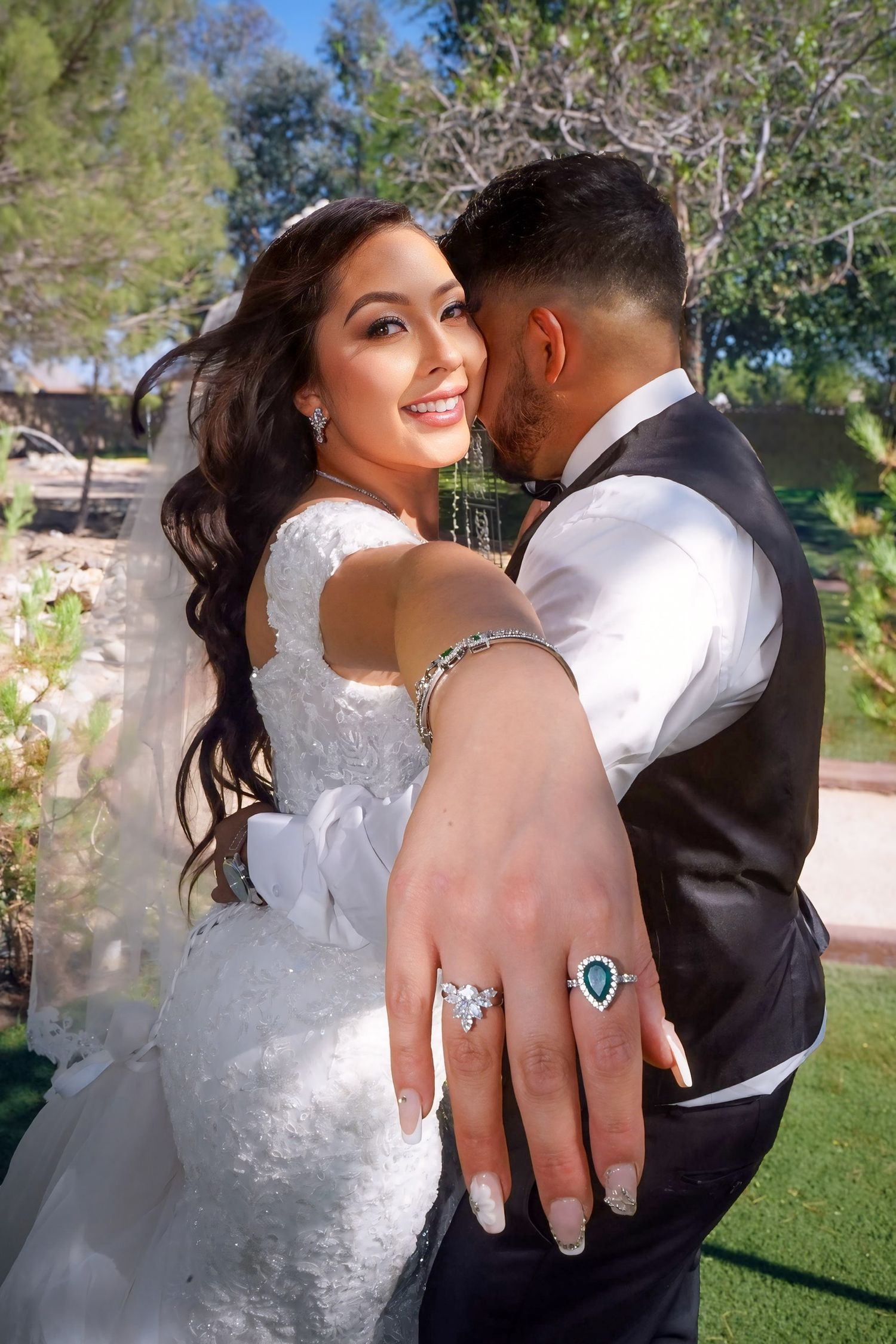 Bride holding up her hand to display her wedding ring while standing with the groom after their outdoor wedding ceremony.