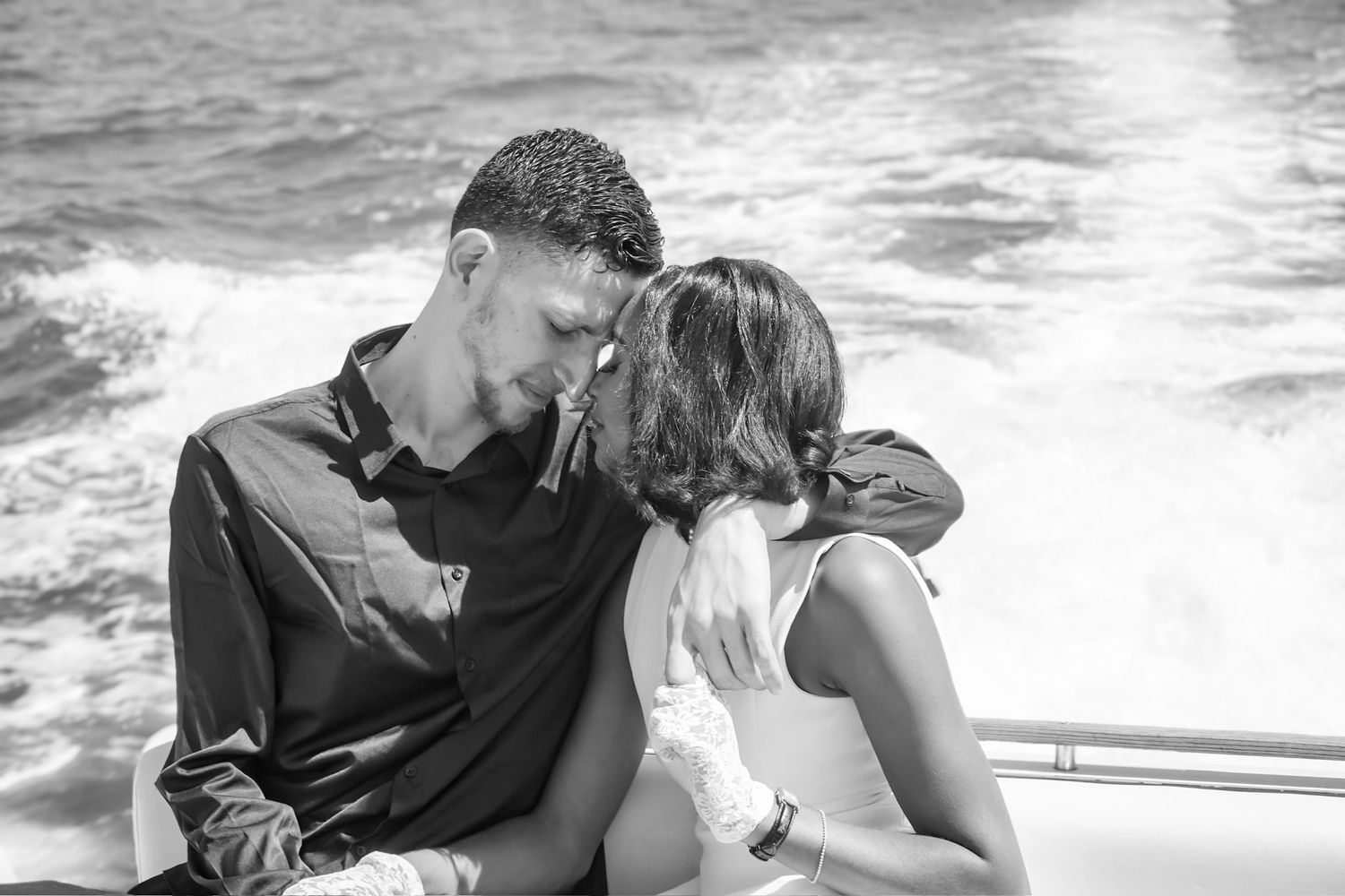 Intimate close up moment of foreheads touching, eyes closed of  couple during engagement shoot while riding in the back of a speed boat.