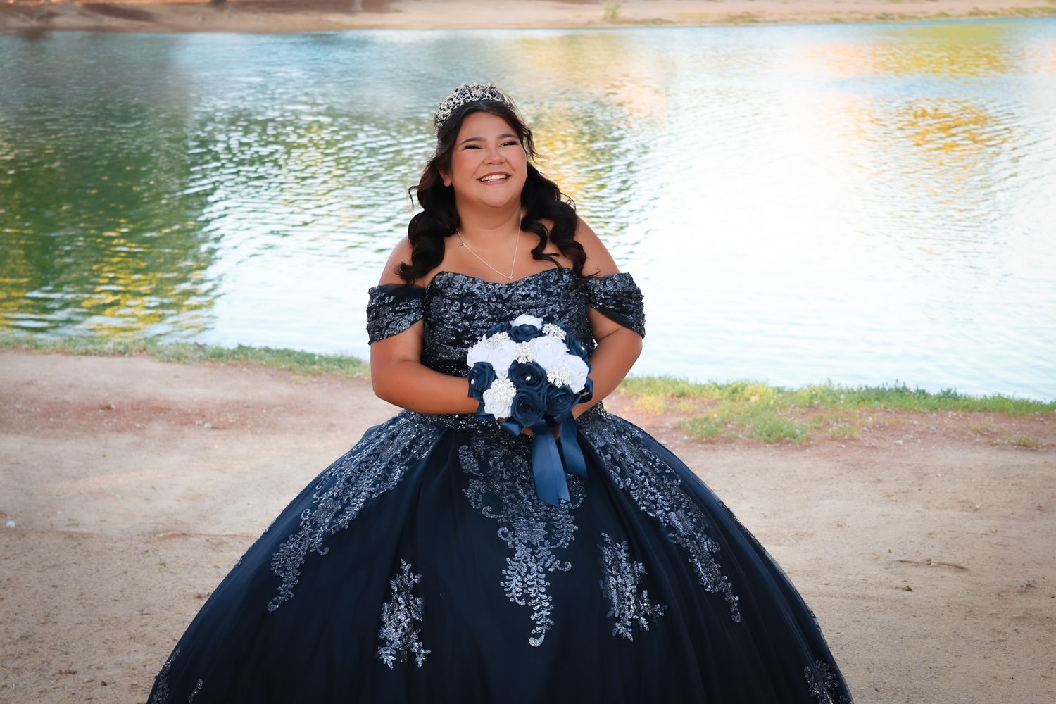 Girl wearing a luxe blue dress holding a faux blue and white bouquet near a lake.