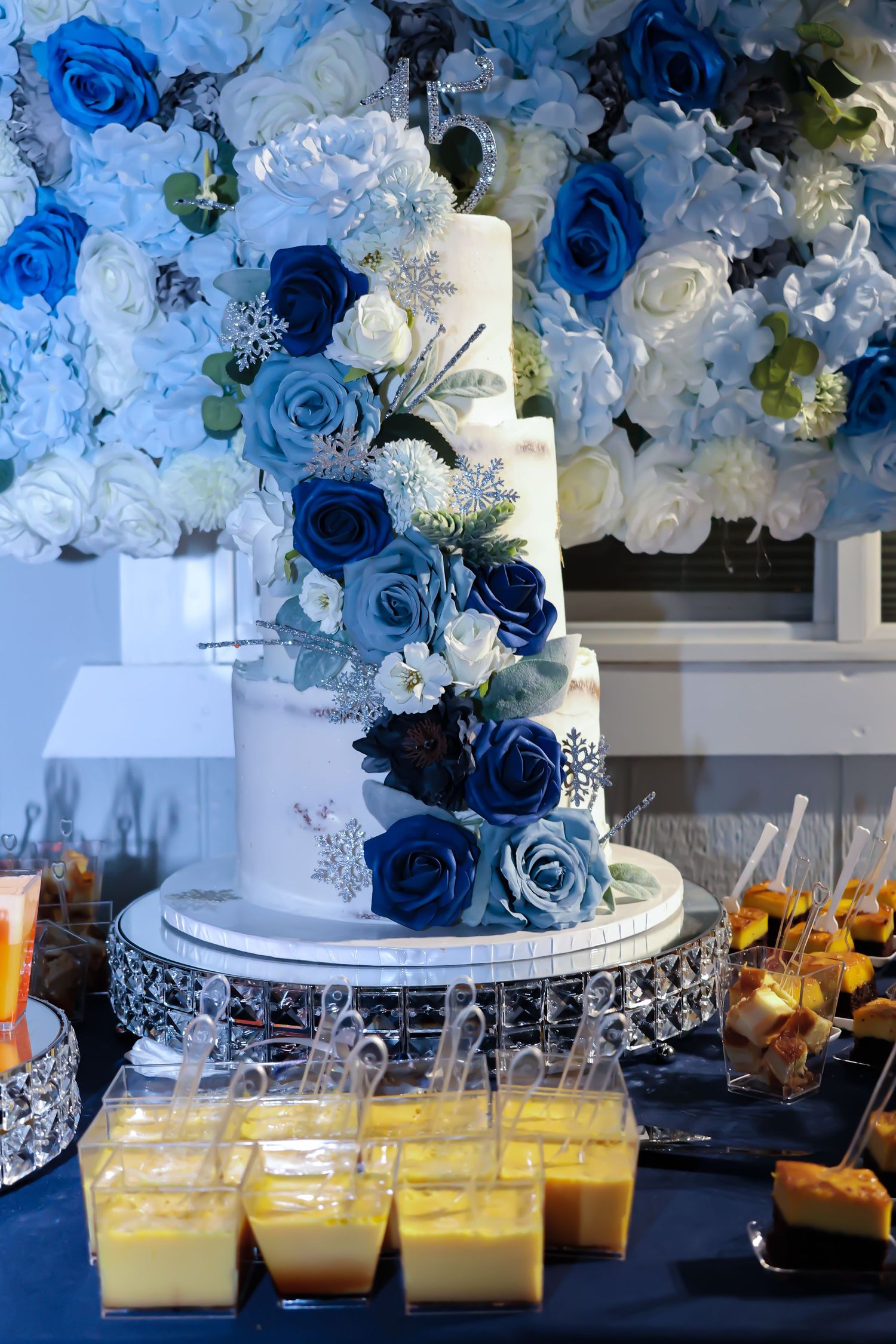 Three tier grand white cake decorated carefully with different hues of blue and white roses.