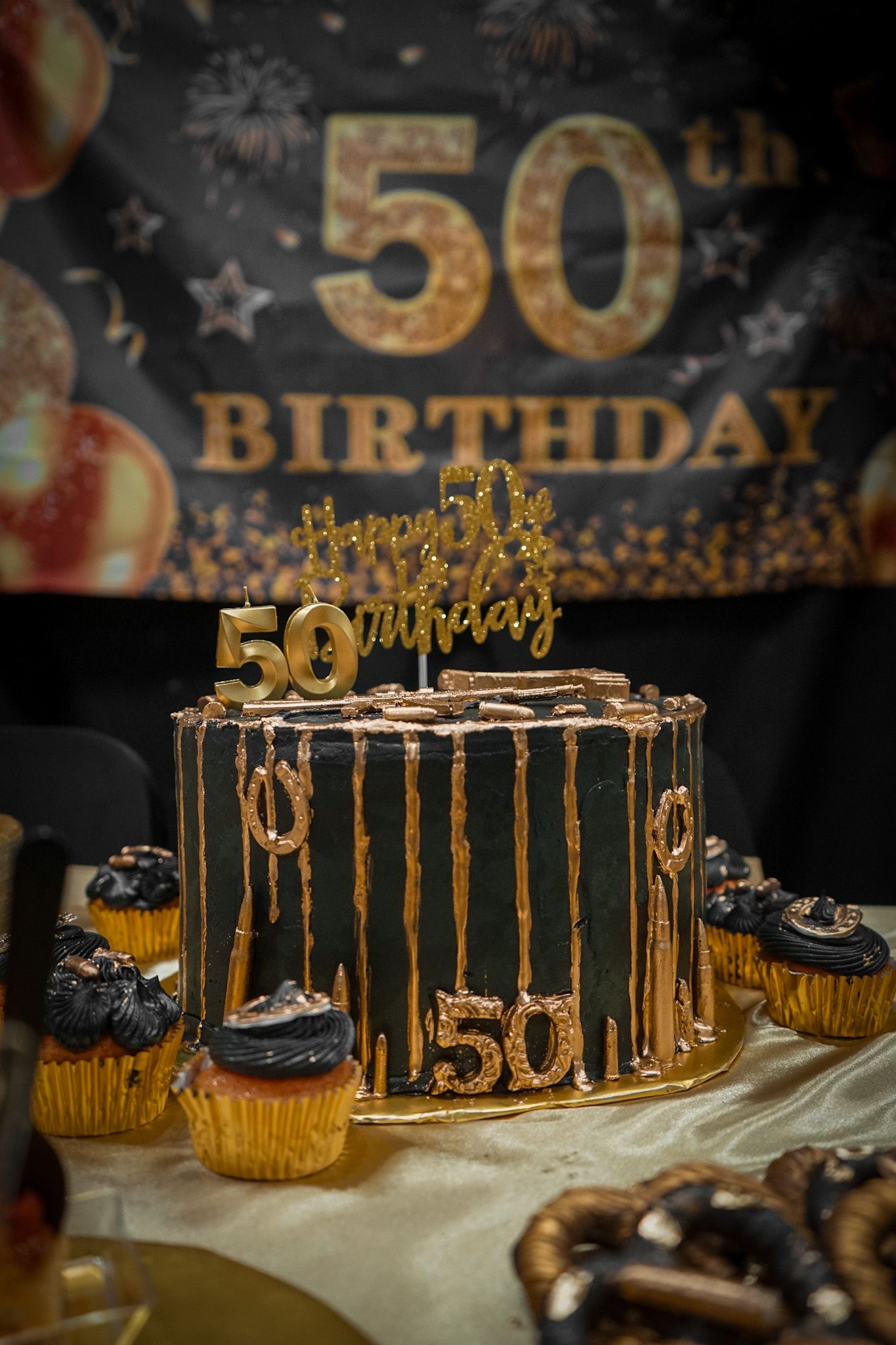 Close up of decadent Black iced cake with gold dripping from the edges for a milestone 50th birthday celebration.