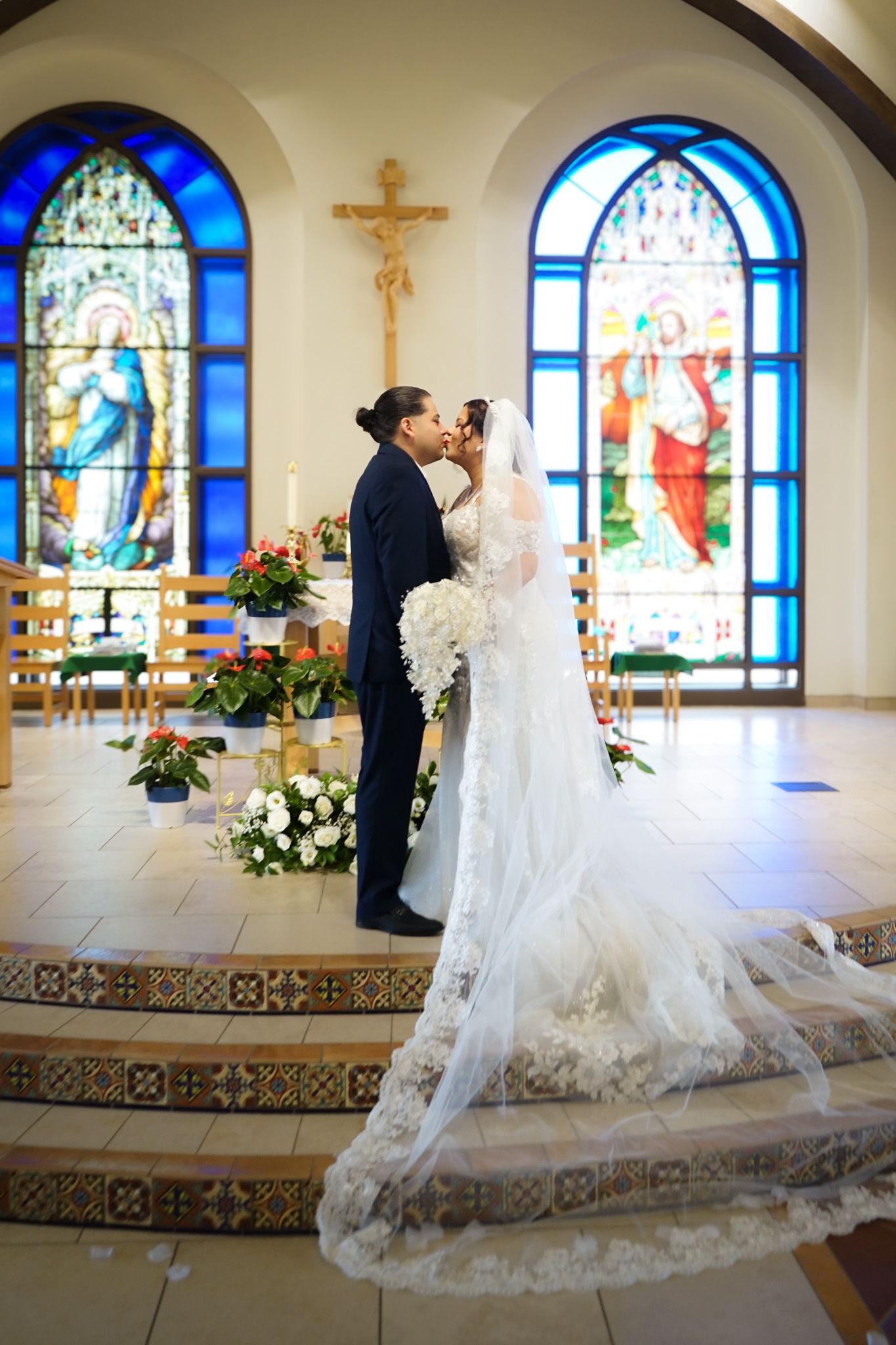 Newlyweds sharing a kiss at the altar immediately after their wedding ceremony, surrounded by church pews and soft natural light.