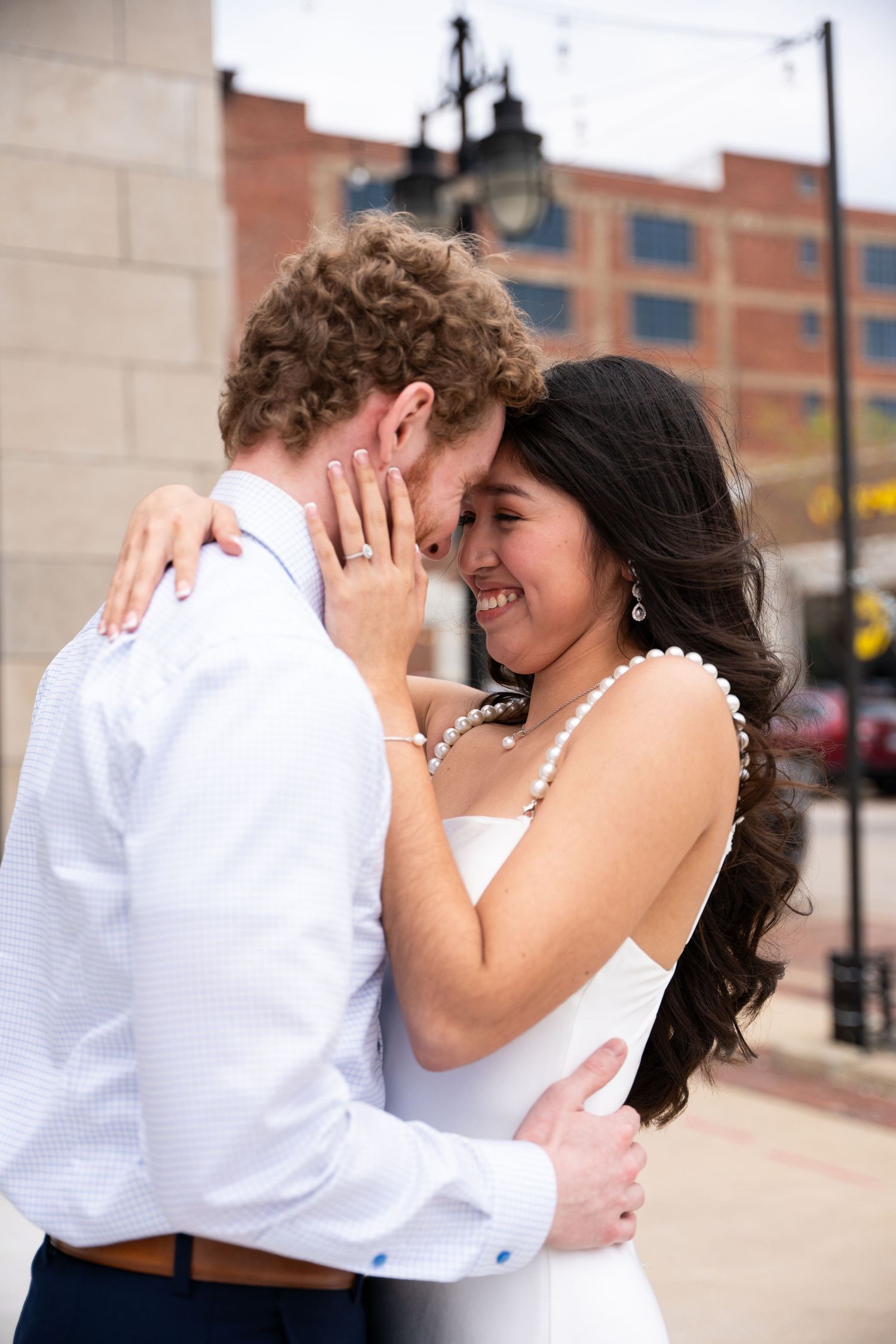 Romantic couple embracing and dancing together against a brick building backdrop.
