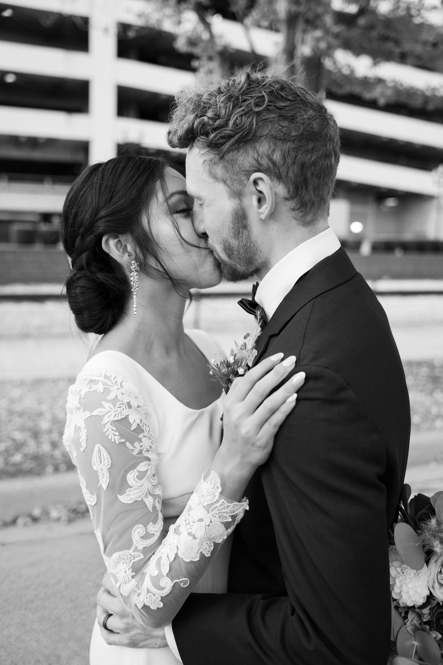 Black and white romantic wedding portrait showing couple in lace dress and dark suit sharing an intimate moment.