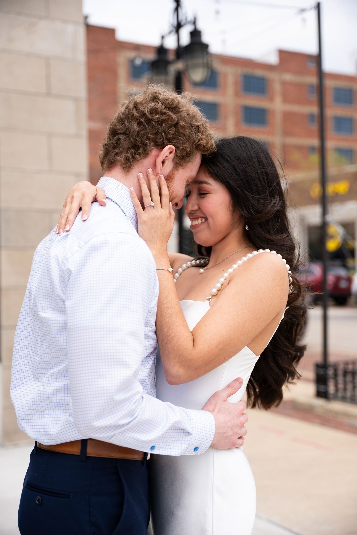 Romantic couple embracing and laughing together outside a brick building.