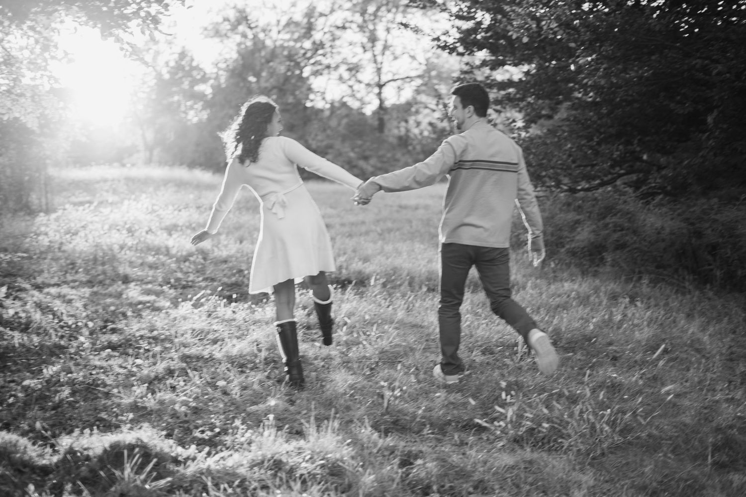 Playful couple running through misty field during outdoor photo session.