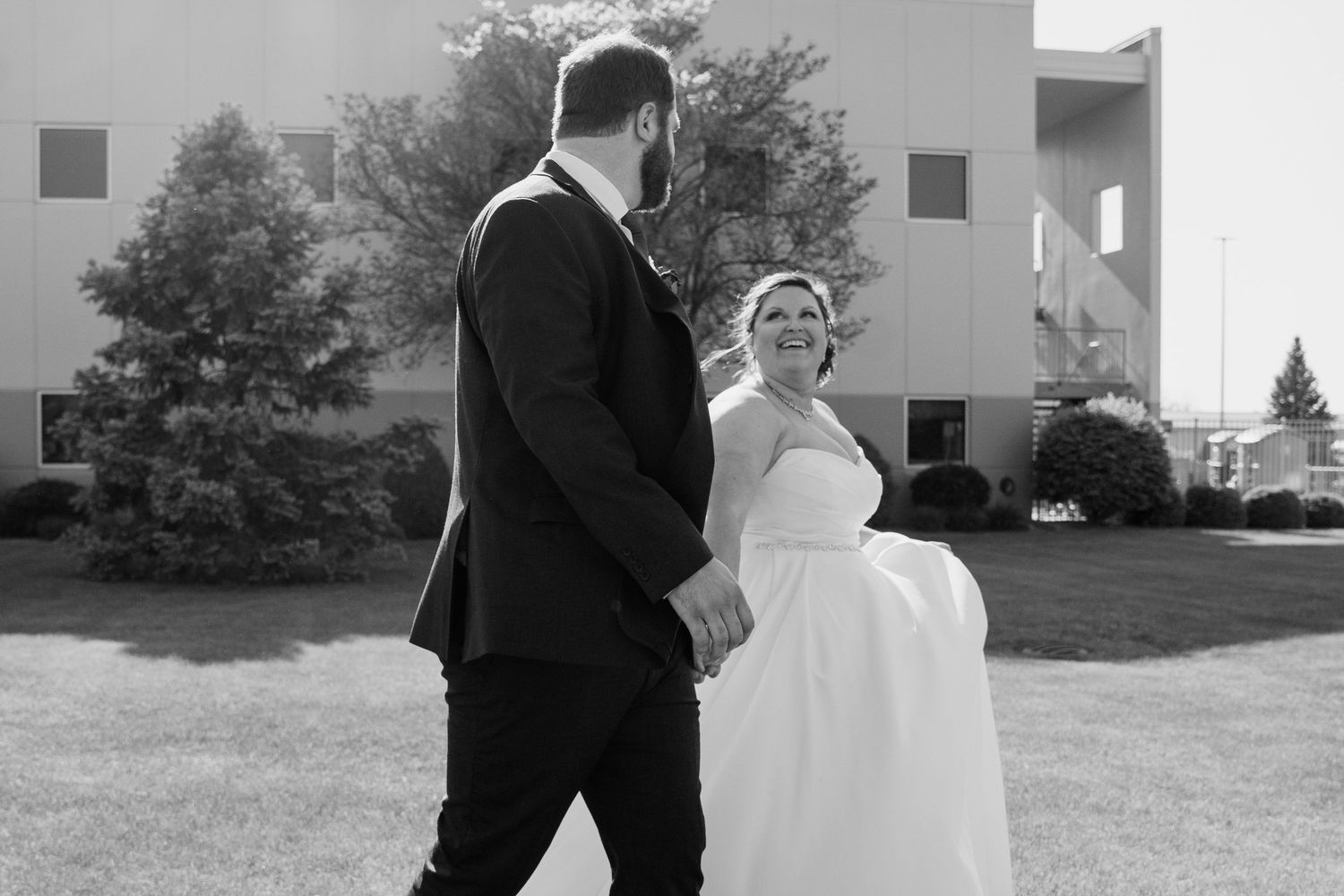 Black and white wedding photos showing couple embracing outdoors near white buildings.