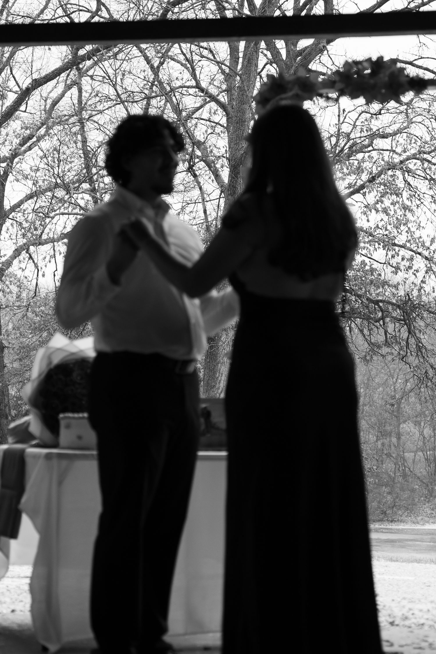 Black and white silhouettes of a couple dancing together outdoors.