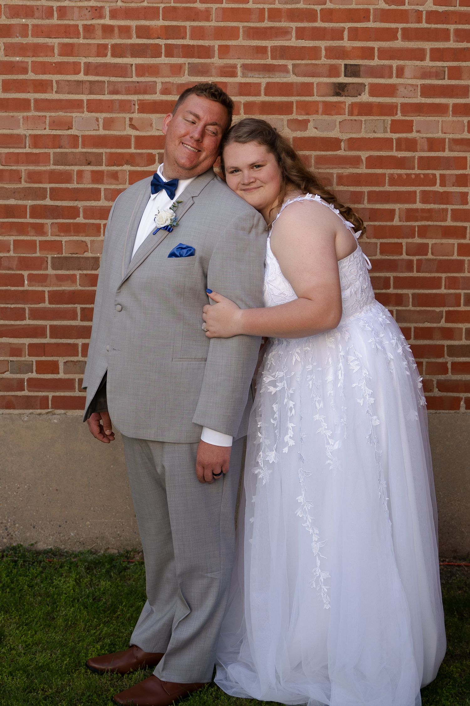 Series of romantic poses of a couple in wedding attire against a brick wall exterior.