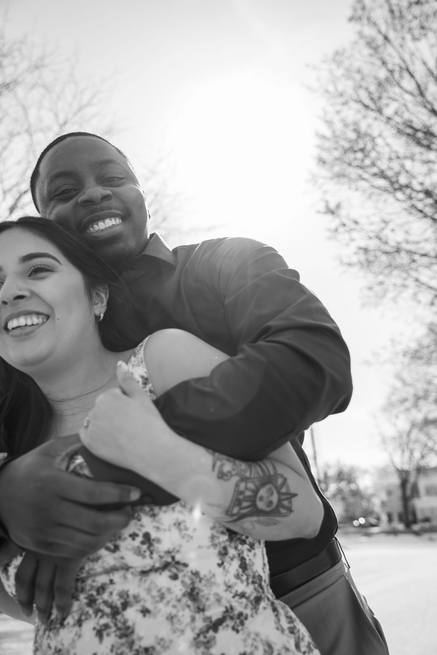A joyful couple embraces outdoors on a bright sunny day.