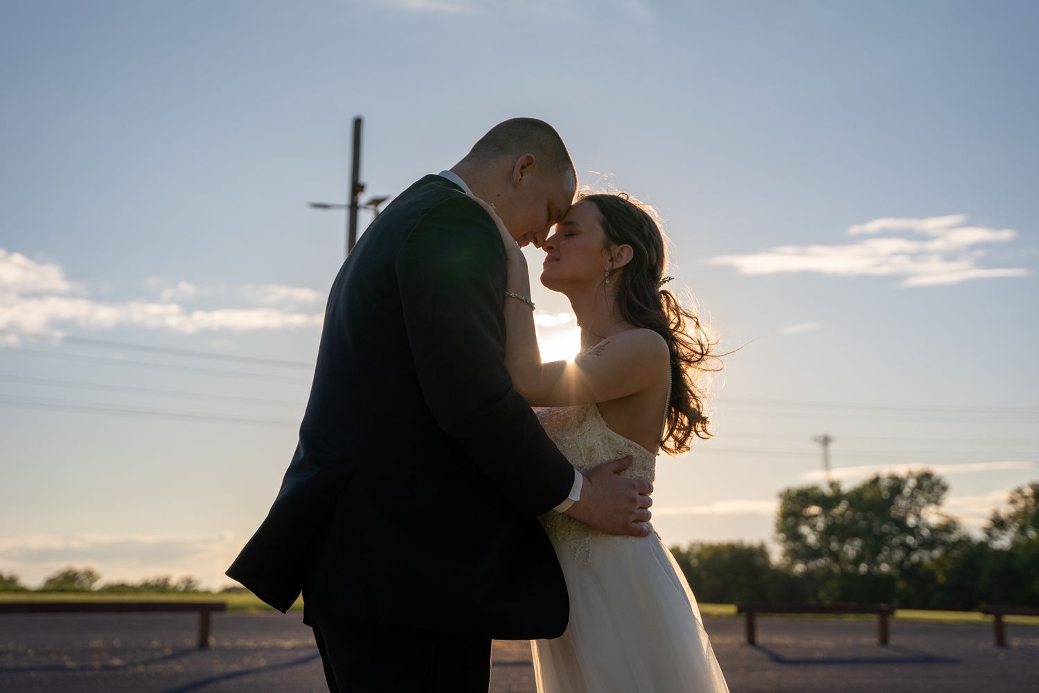 Silhouetted couple shares tender moments against a sunset sky.
