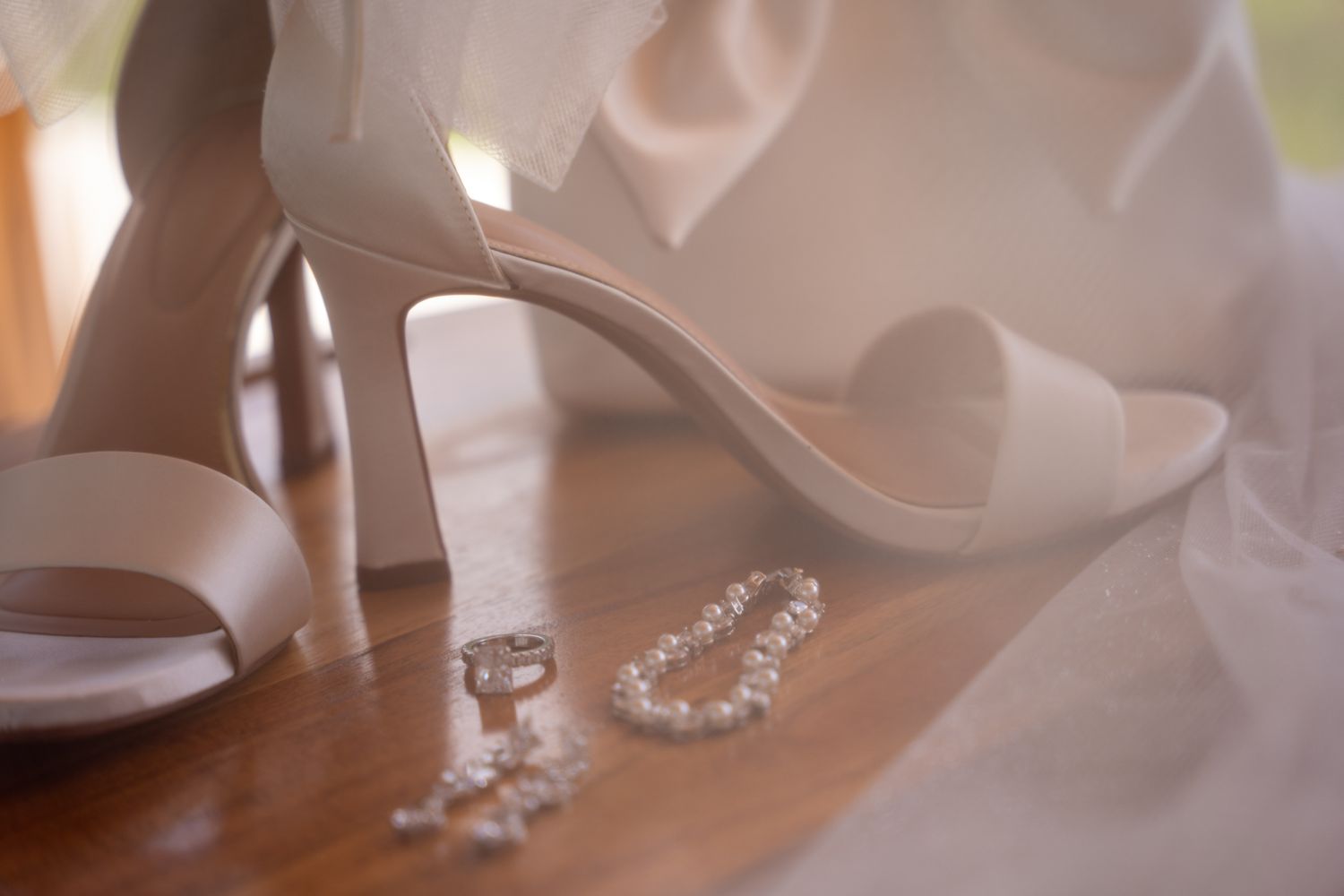 Wedding rings and jewelry details arranged artistically on white fabric.