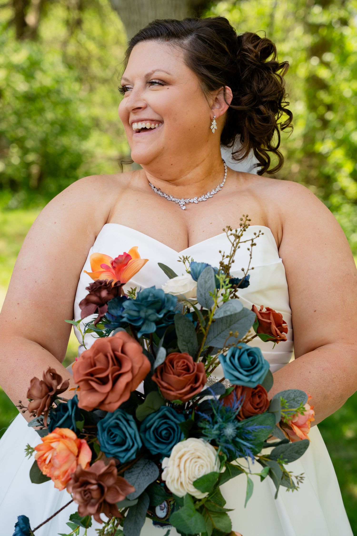 Bridal bouquet featuring teal and rust-colored roses with white accents against a natural background.