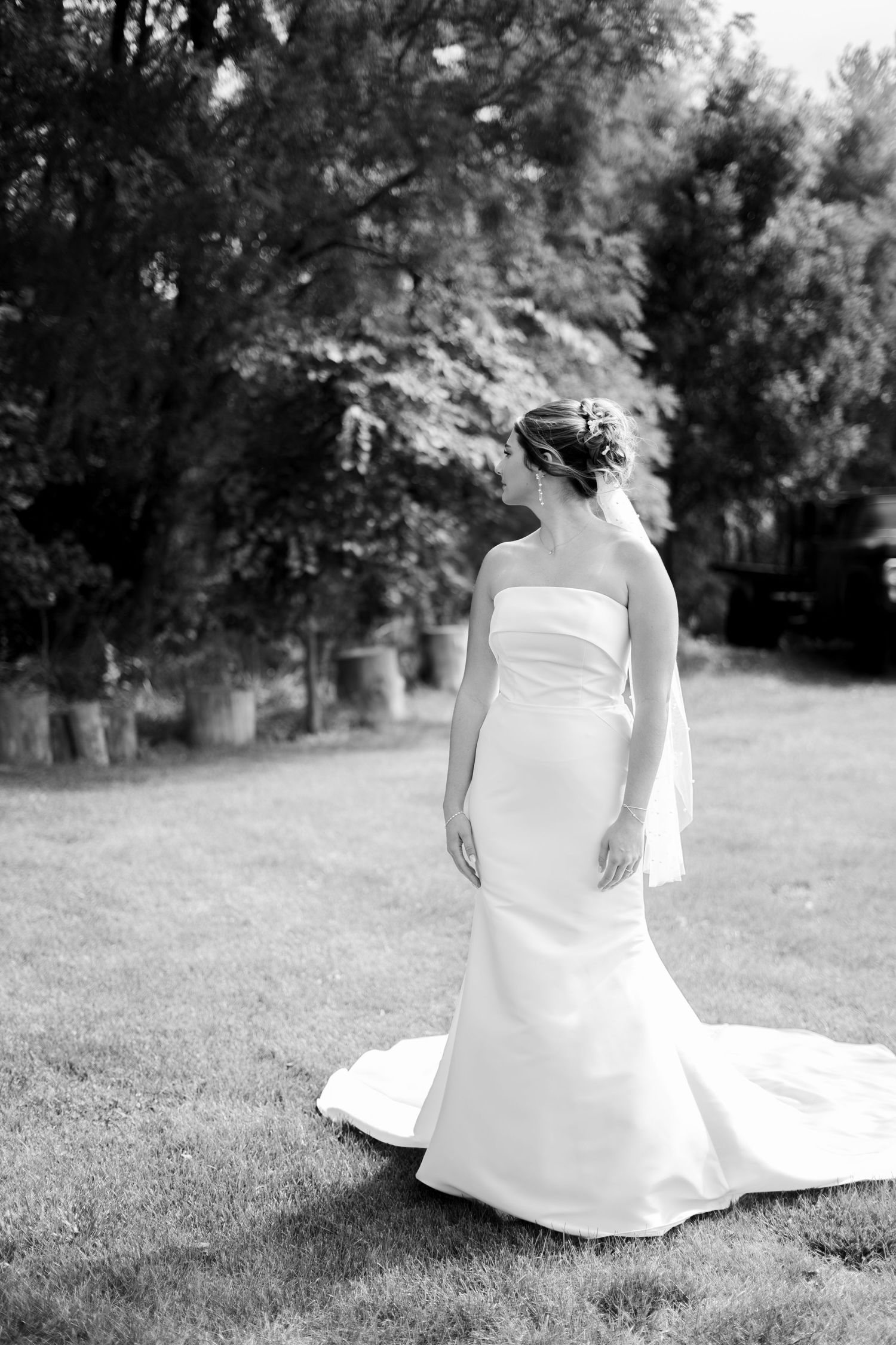 Black and white portrait series of bride sitting gracefully on grass in flowing white dress.