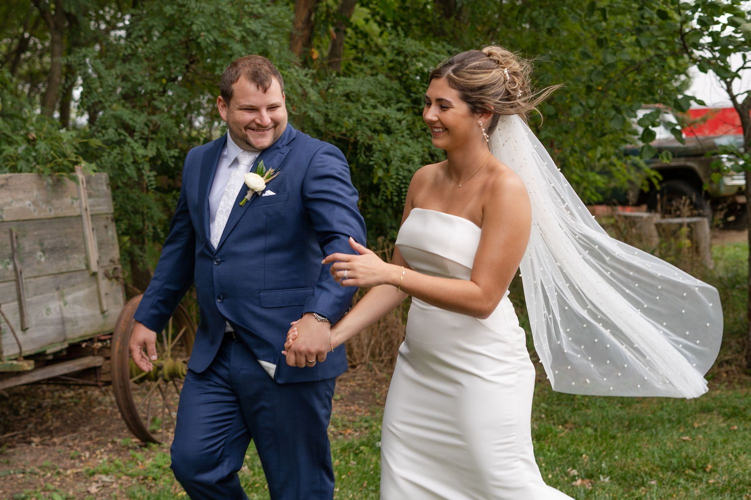 Playful outdoor wedding photos with couple in navy suit and white dress.
