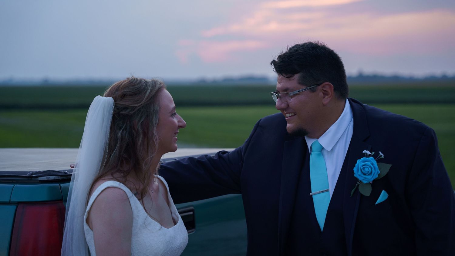 Silhouetted couple in formal wear photographed against dramatic sunset sky.
