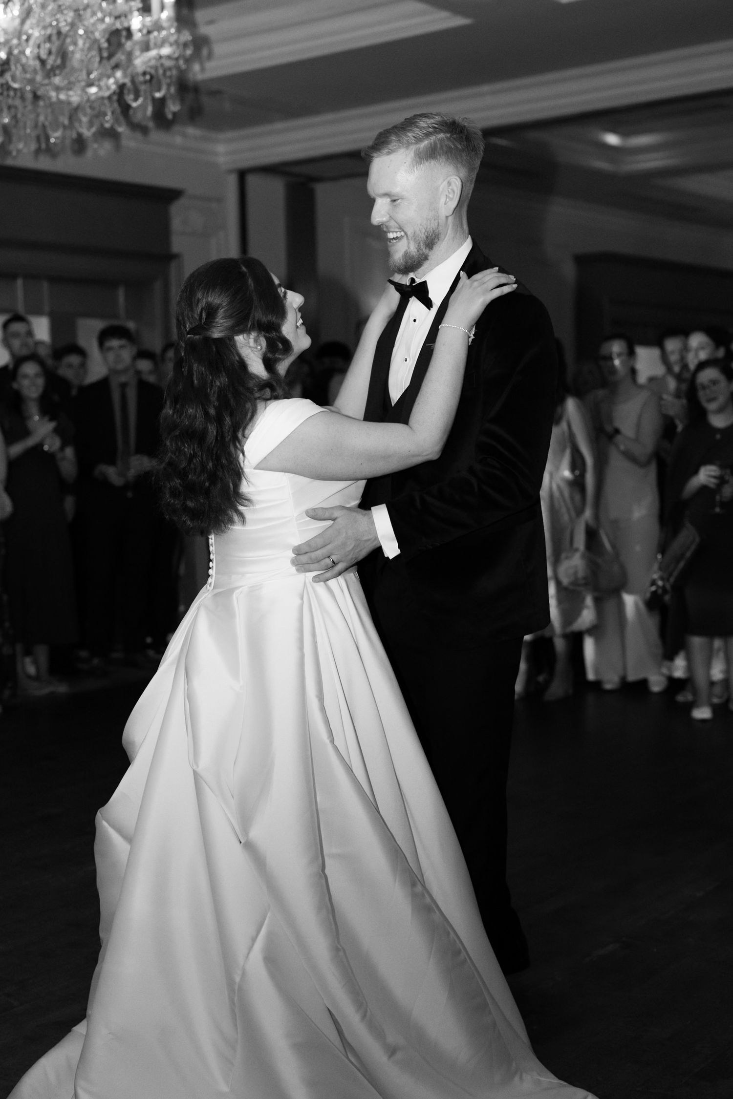Black and white photo of bride and groom sharing their first dance at elegant wedding reception.