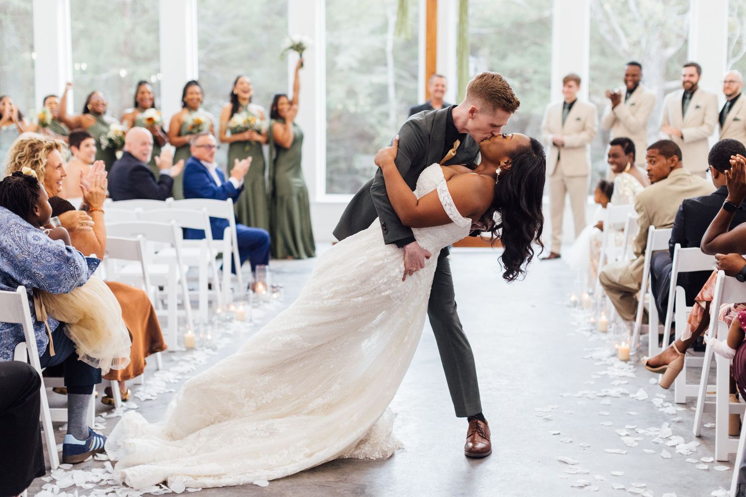 Wedding guests watch as newlyweds share their first dance in an elegant reception venue filled with white decor.