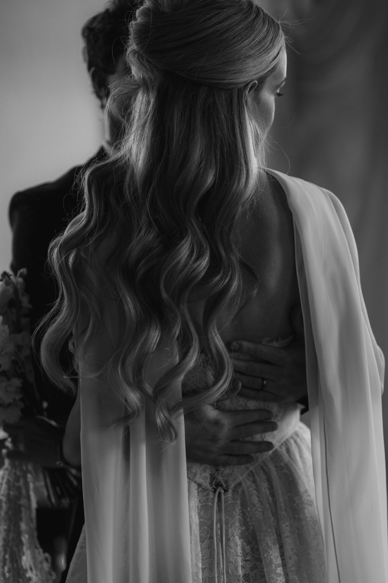 Black and white detail of a bride's flowing hair and veil against a textured background.