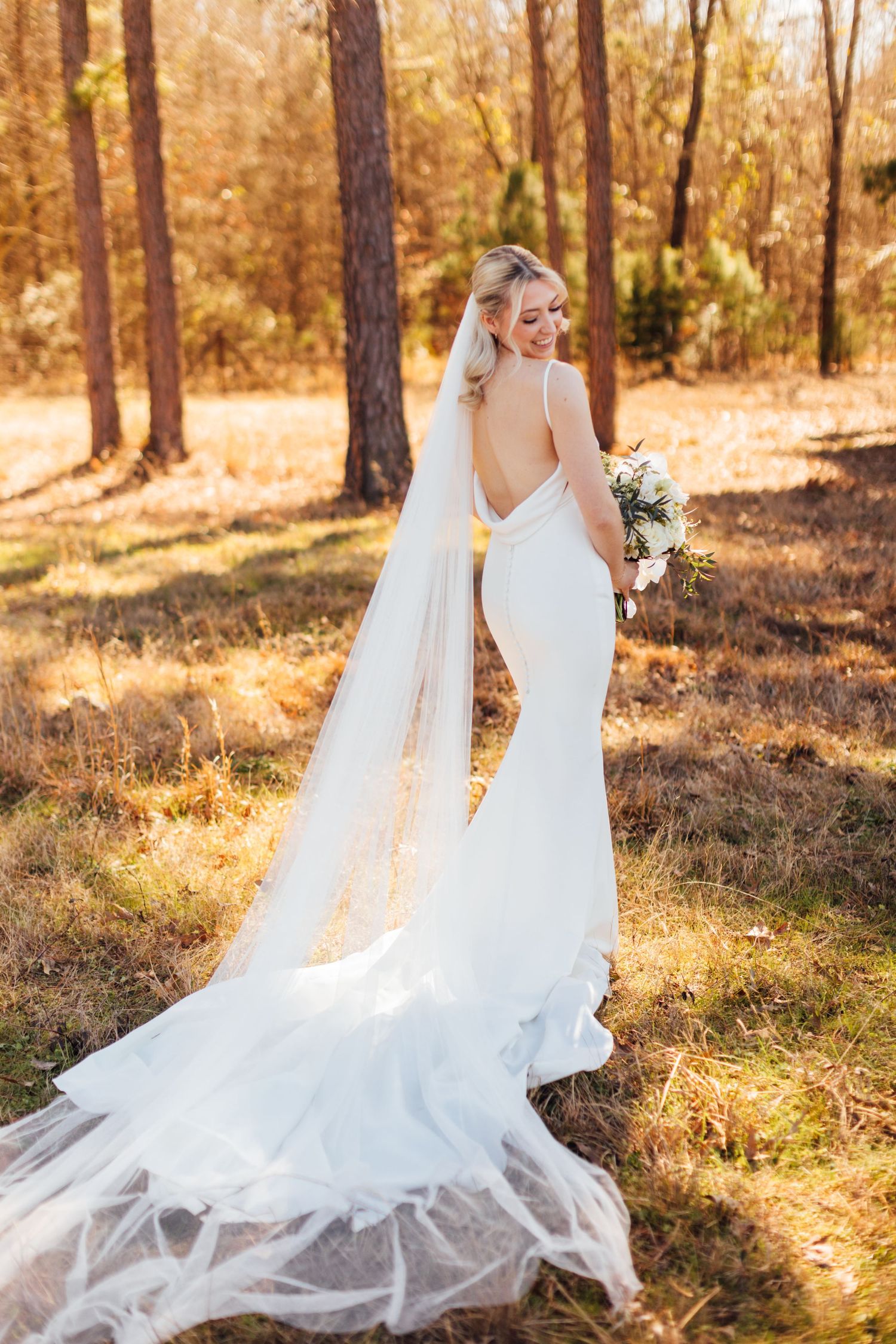 A romantic wedding photoshoot in a sunlit forest with flowing white dresses catching the golden light.