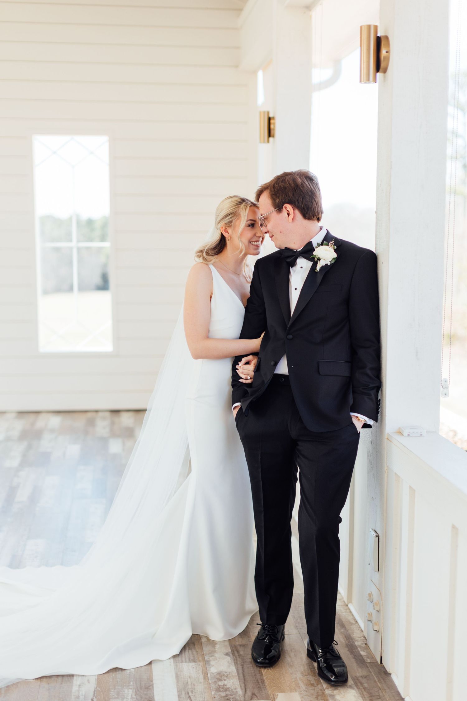 Intimate wedding couple moment captured in bright white chapel hallway.