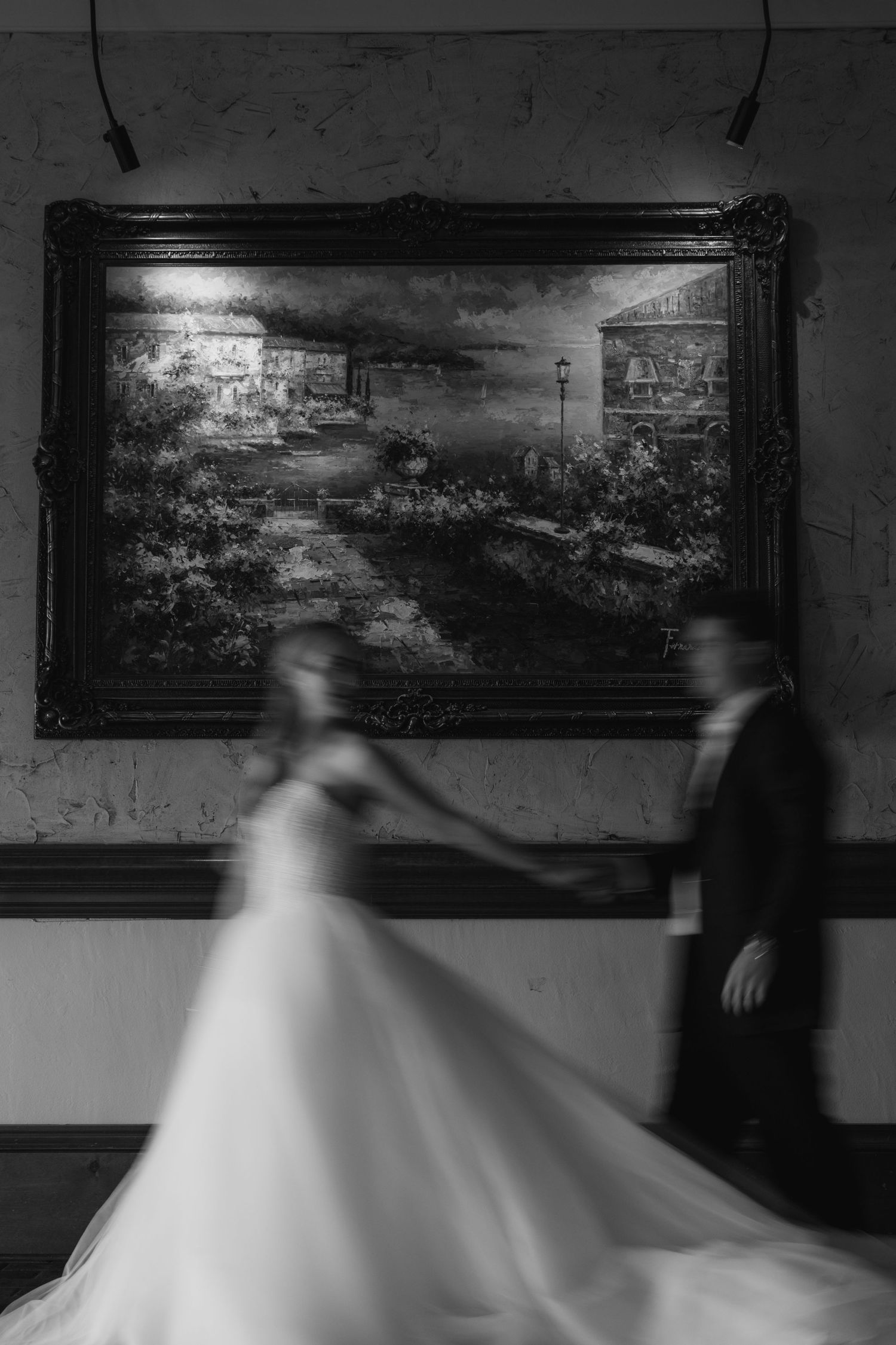 A motion-blurred black and white photograph shows a ghostly figure in a flowing white dress moving through a dark room.