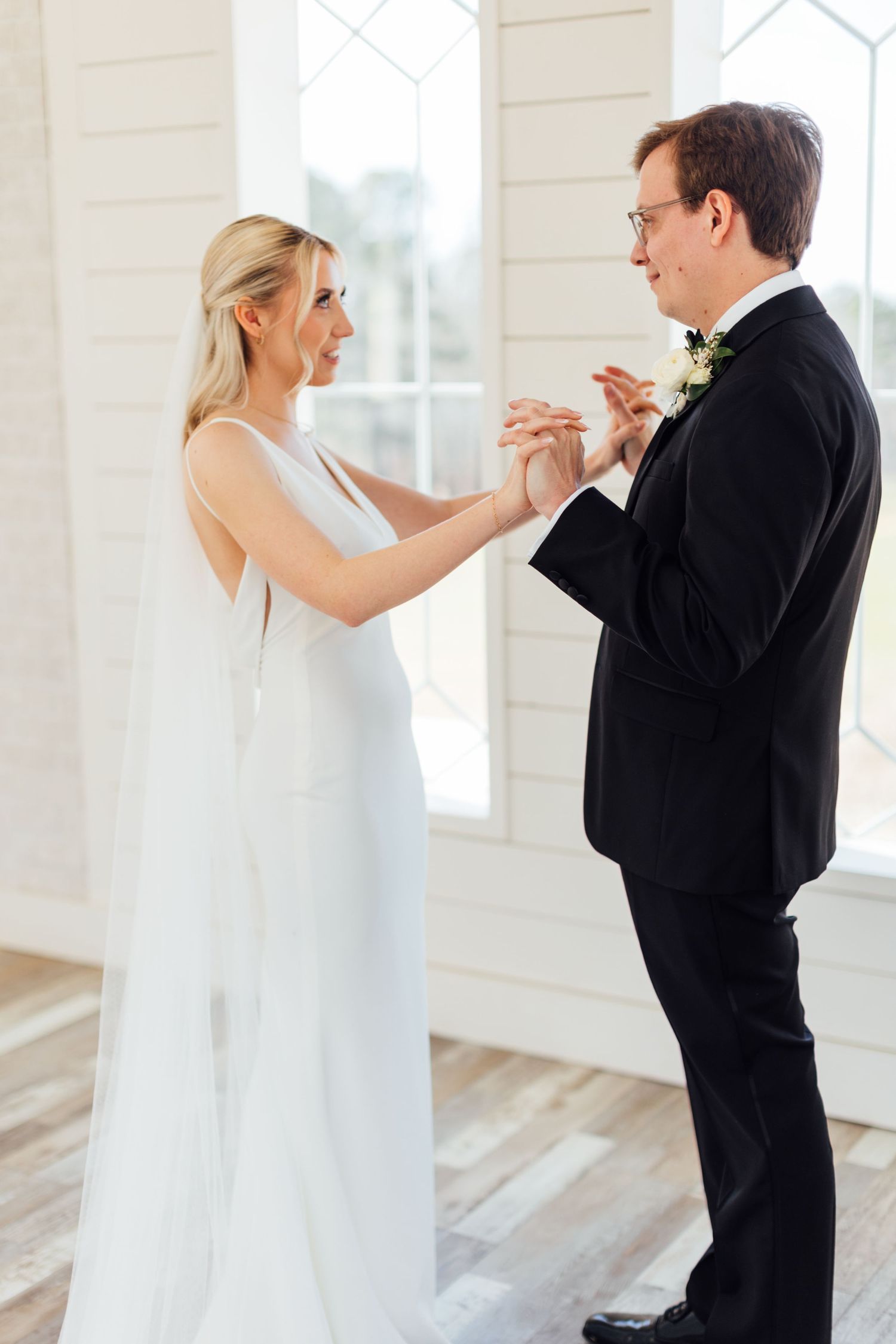 Emotional first look moment between bride and groom in white chapel setting.