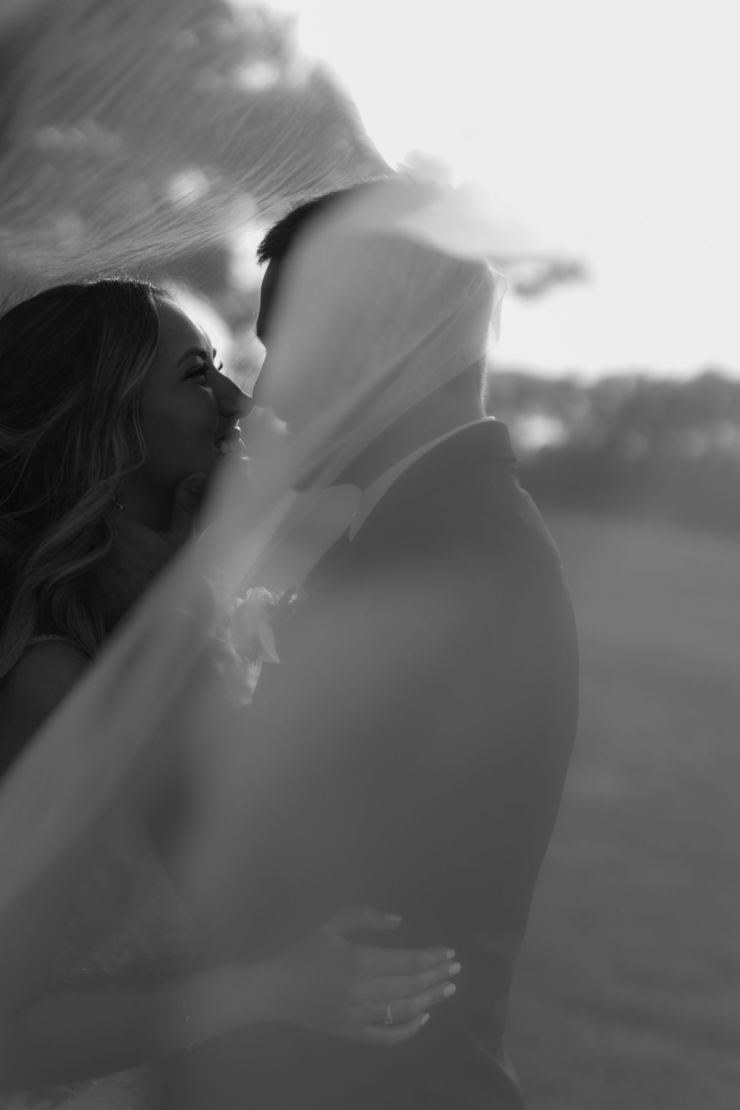 Romantic silhouette of newlyweds sharing an intimate moment under a flowing veil.