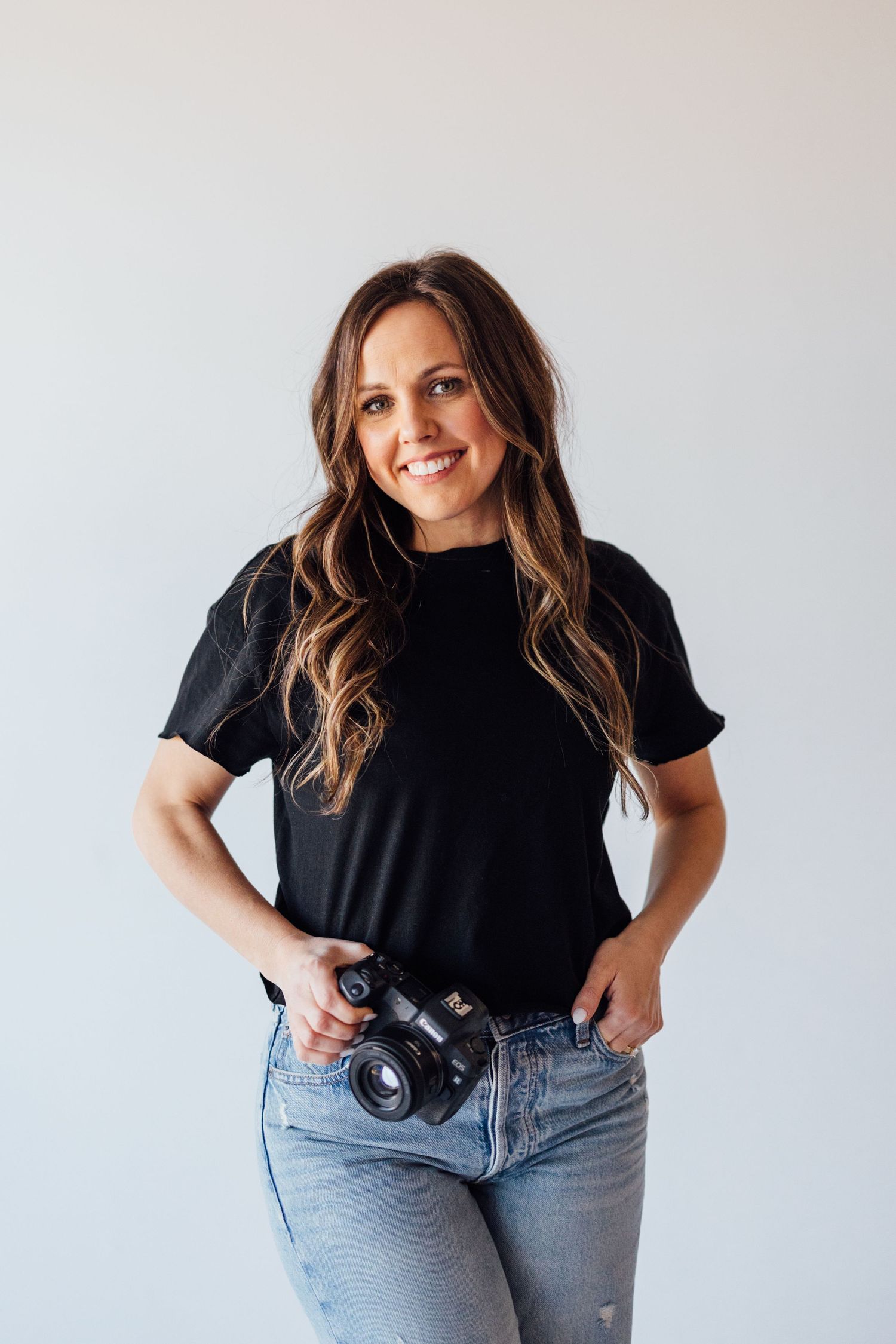 Woman in black t-shirt and light denim jeans poses in three casual fashion shots against white background.