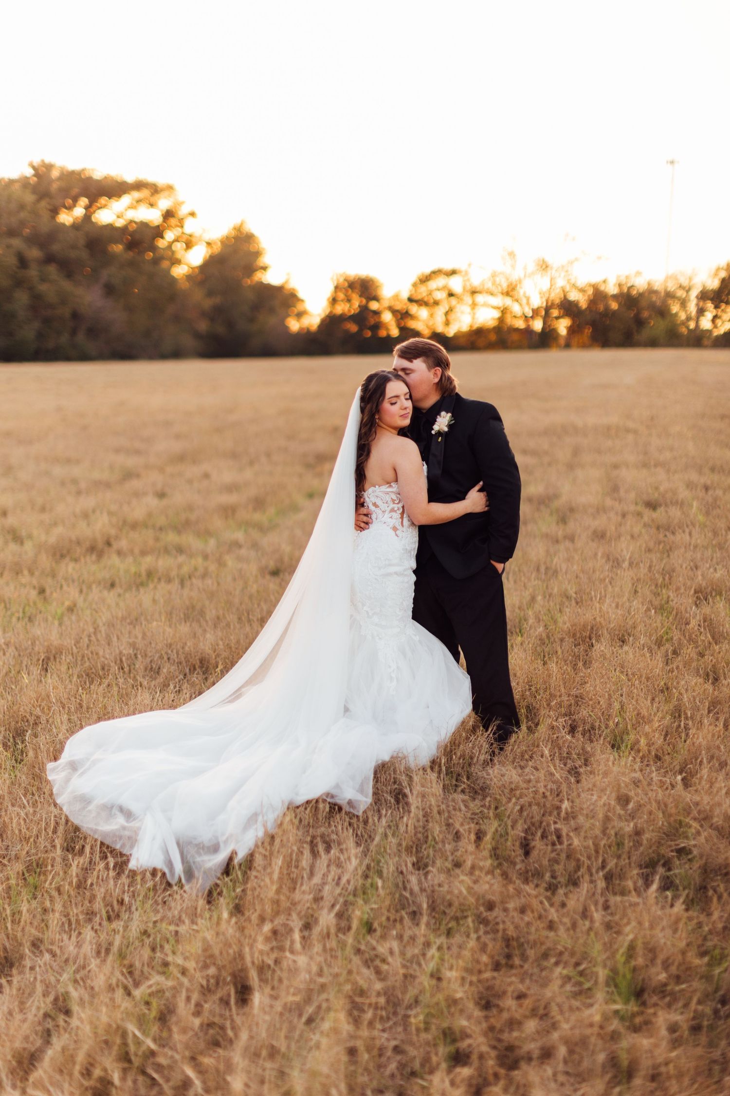 Romantic sunset portraits of couple dancing in golden field with flowing wedding dress.