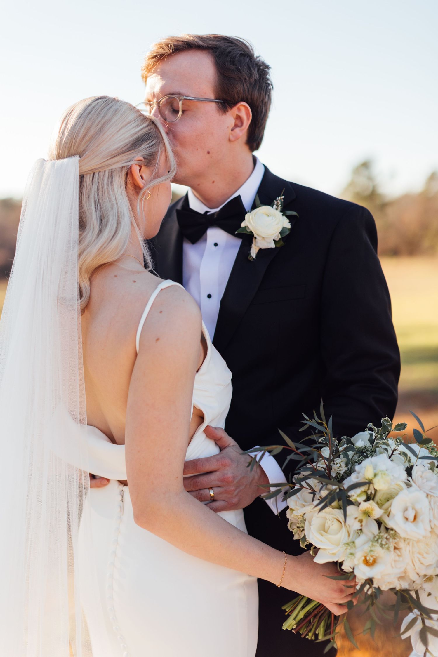 Romantic wedding portraits with white floral bouquet in golden evening light.