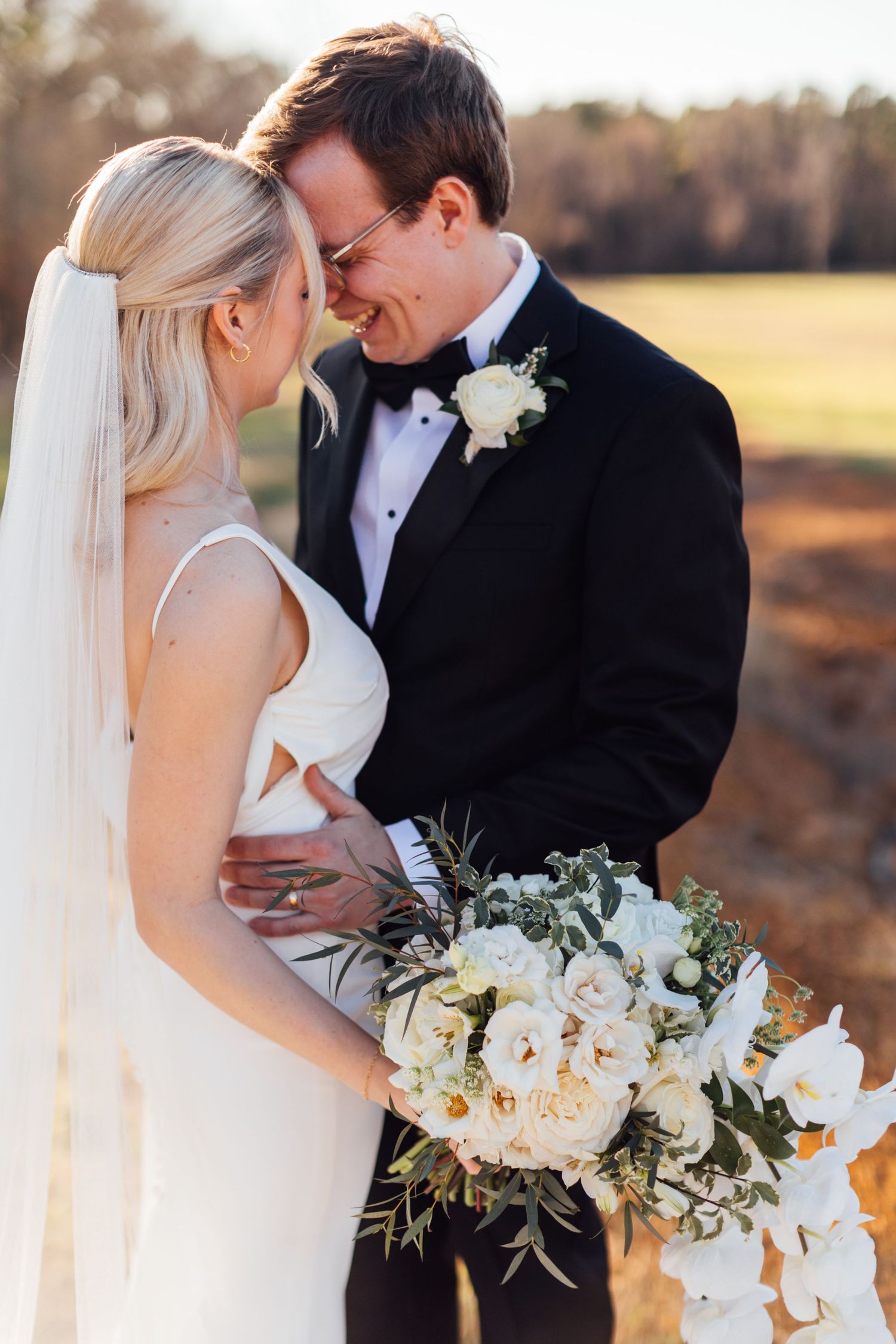 Elegant wedding portraits with white floral bouquet against natural outdoor setting.