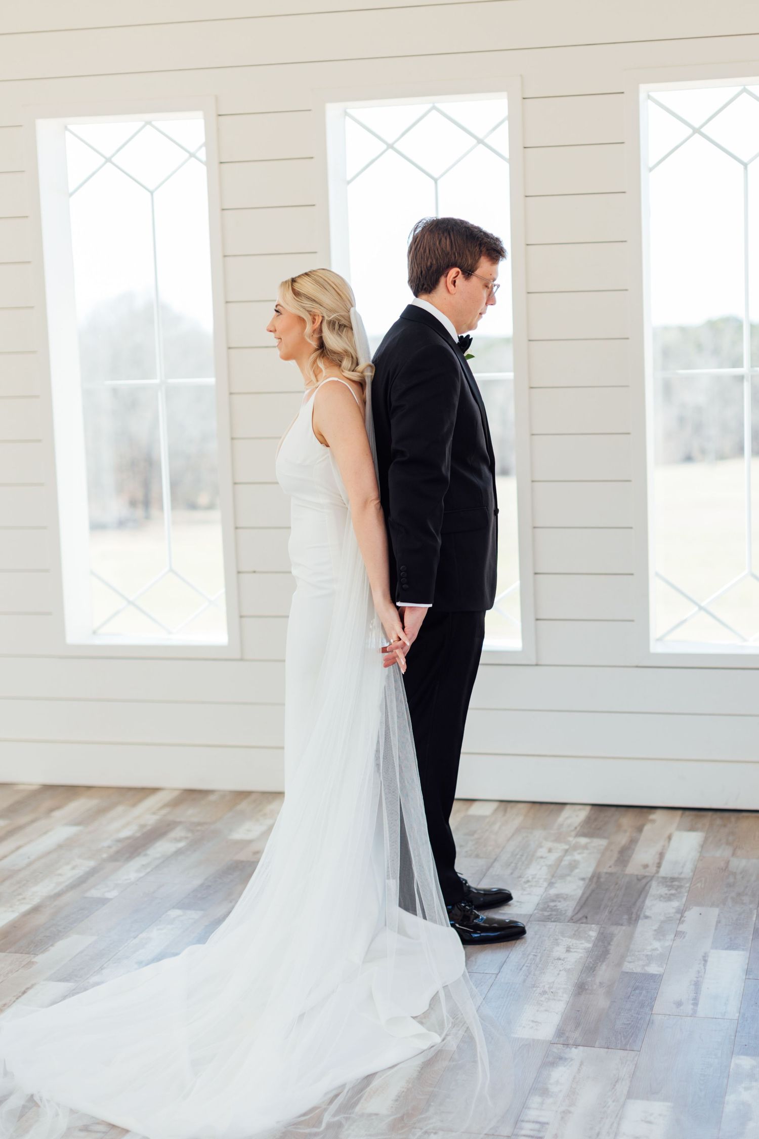 First look sequence shows bride and groom from behind in bright white chapel space.