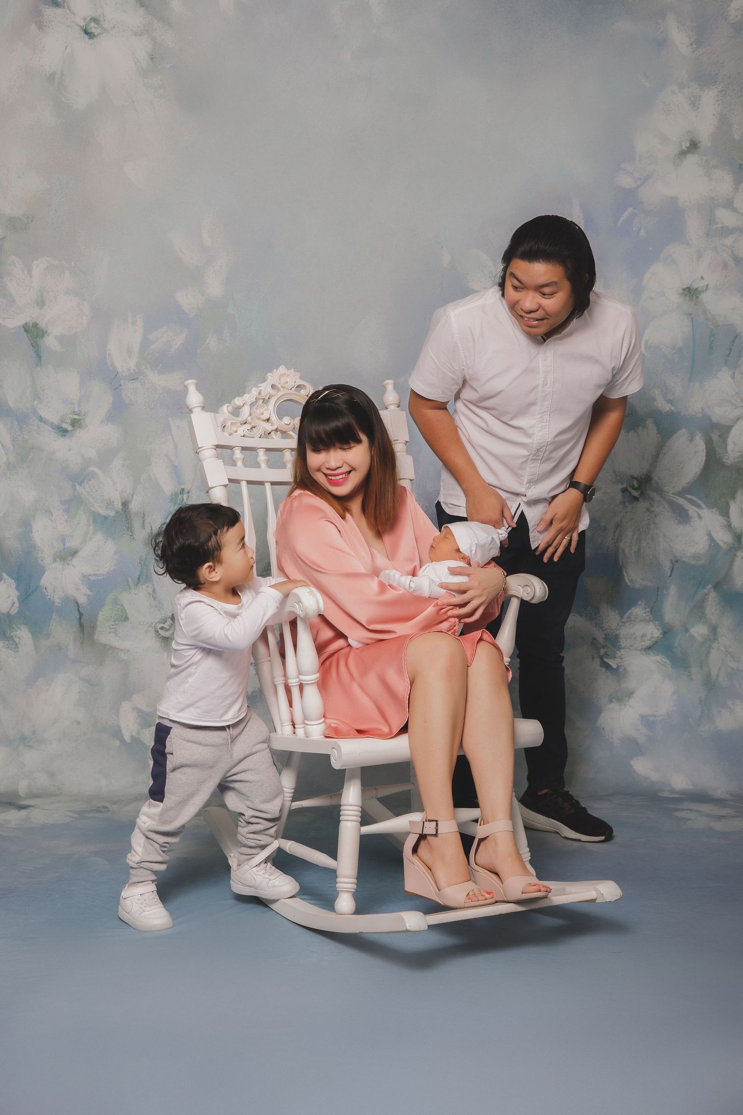 A heartwarming family photoshoot sequence showing tender moments of interaction between parents and child on a cloudy backdrop.