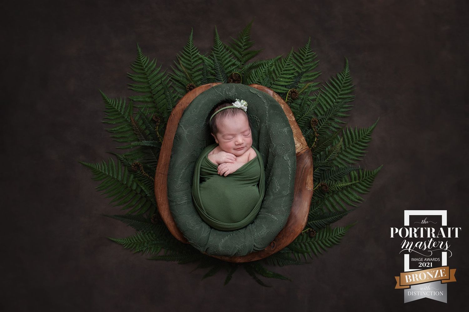 Green fern leaves and dried flowers create a rustic nature-inspired newborn photography backdrop.