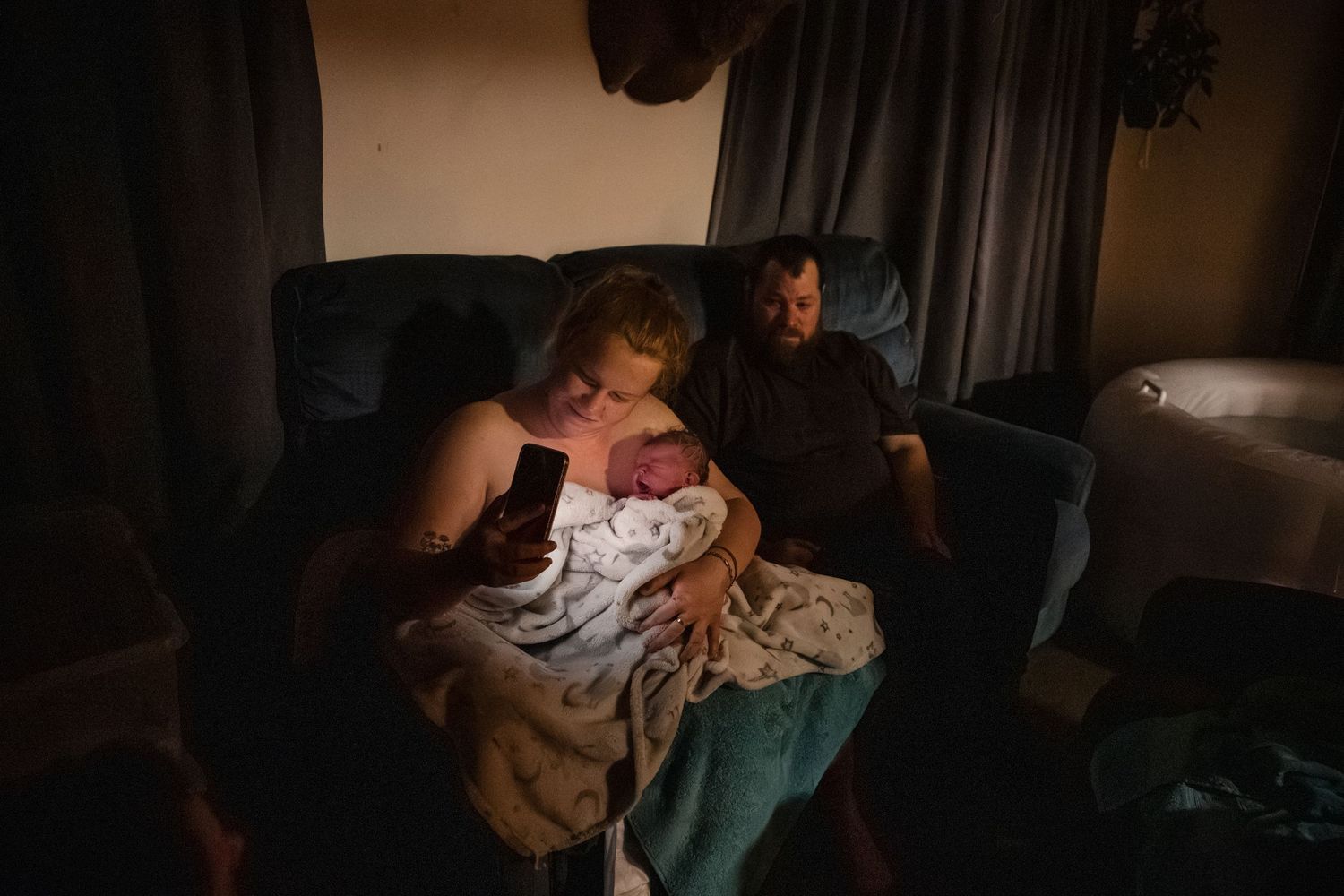 Moody indoor photoshoot showing tender moments between people in low-light conditions.