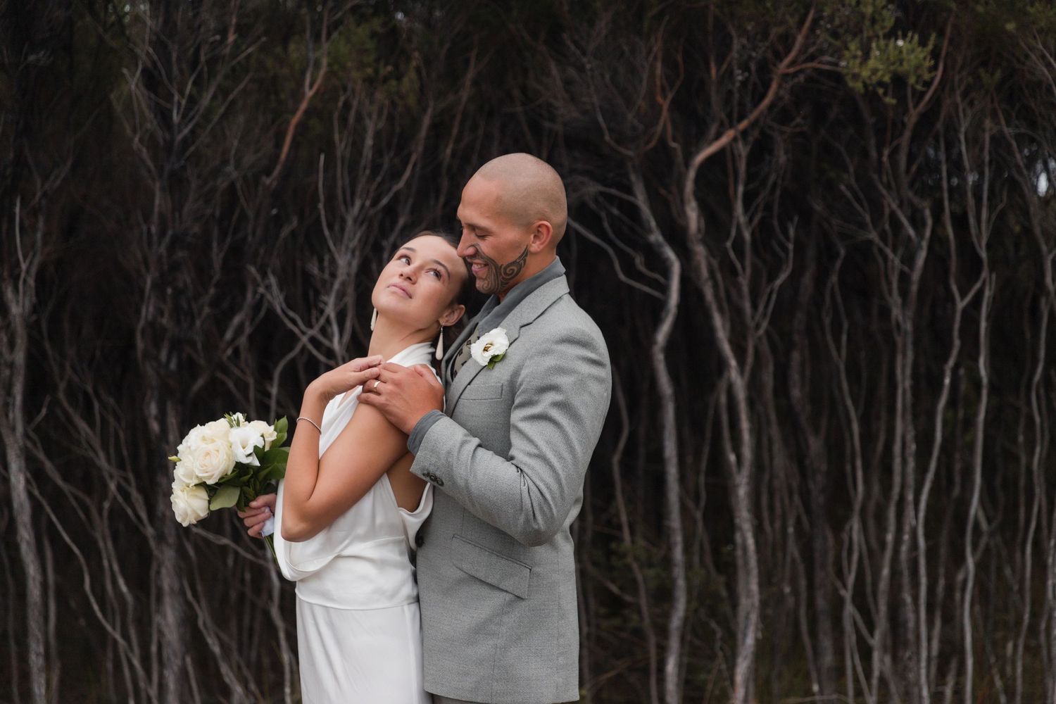 Wedding couple shares intimate moment against dramatic dark forest backdrop. Cambridge Waikato NZ Photographer. White Locket Photography