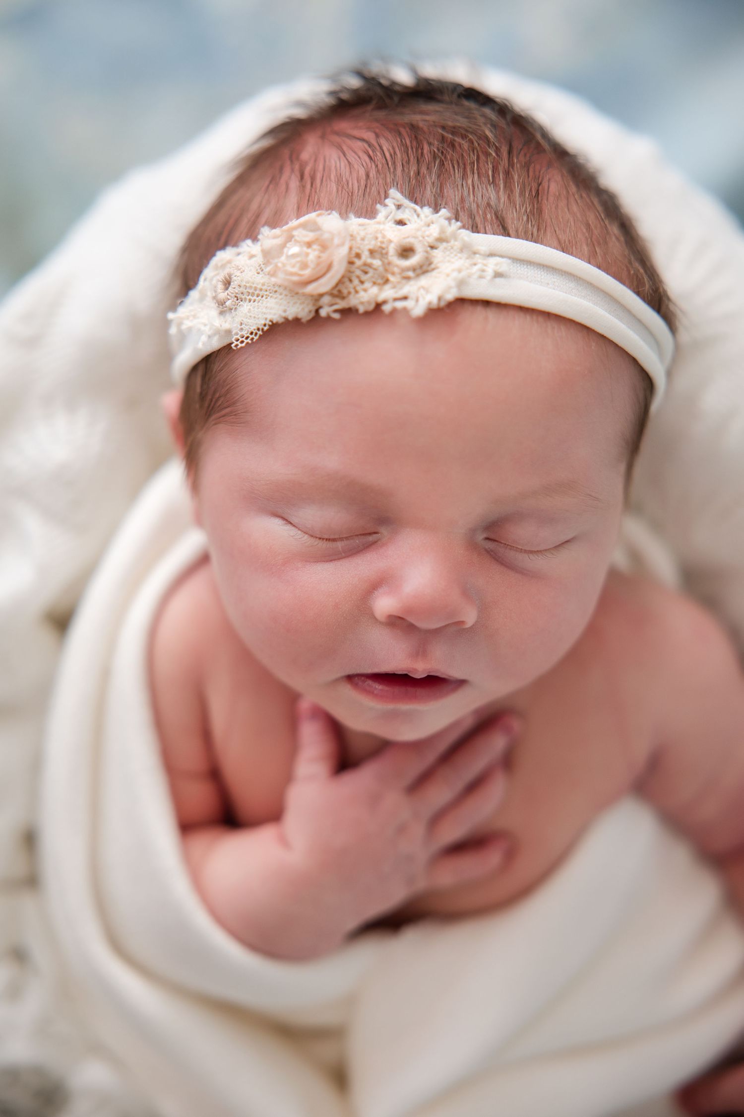 Close-up portrait series showing a sleeping newborn wrapped in white fabric against a blurred background.