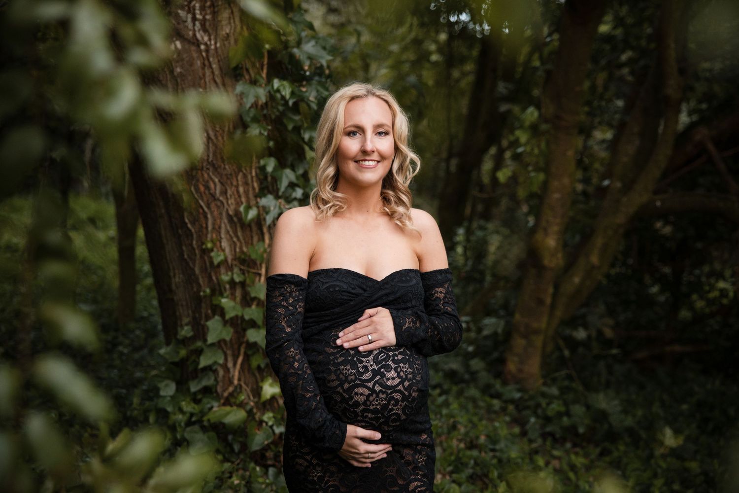 Professional outdoor portrait photography session featuring a person in black attire against a natural wooded backdrop.