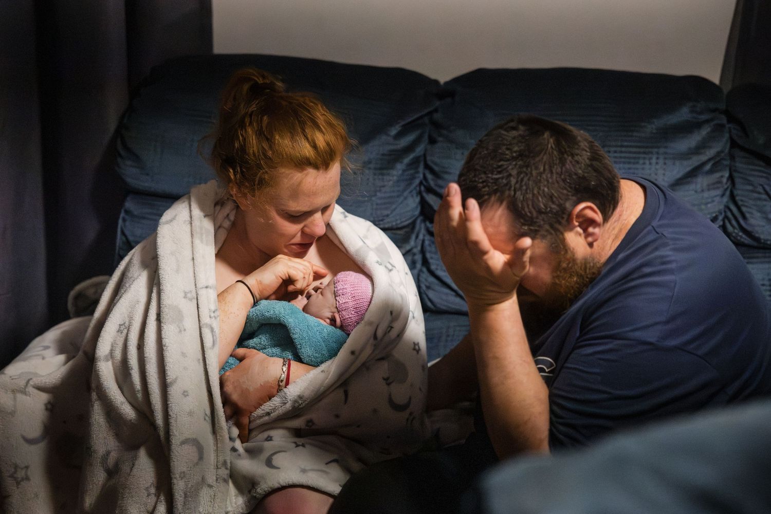 A tender moment between parents and newborn baby in a hospital room with natural lighting.