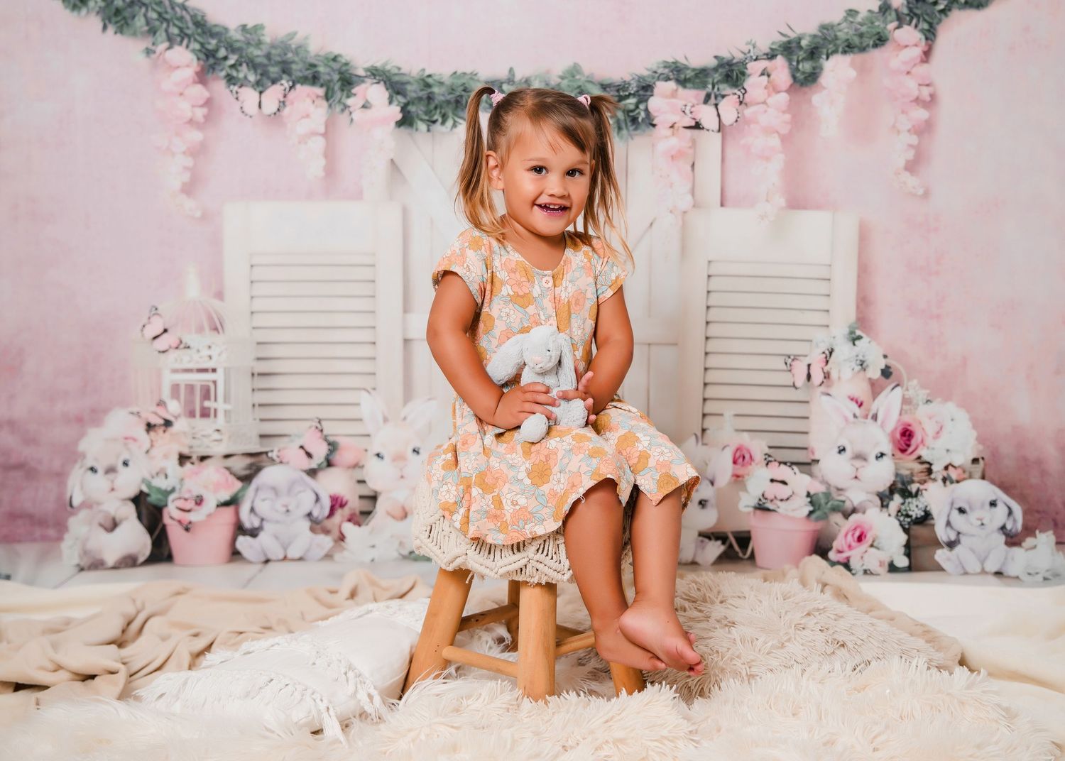 Decorated pink Easter backdrop with bunnies and floral garlands creates a charming spring photo setting.