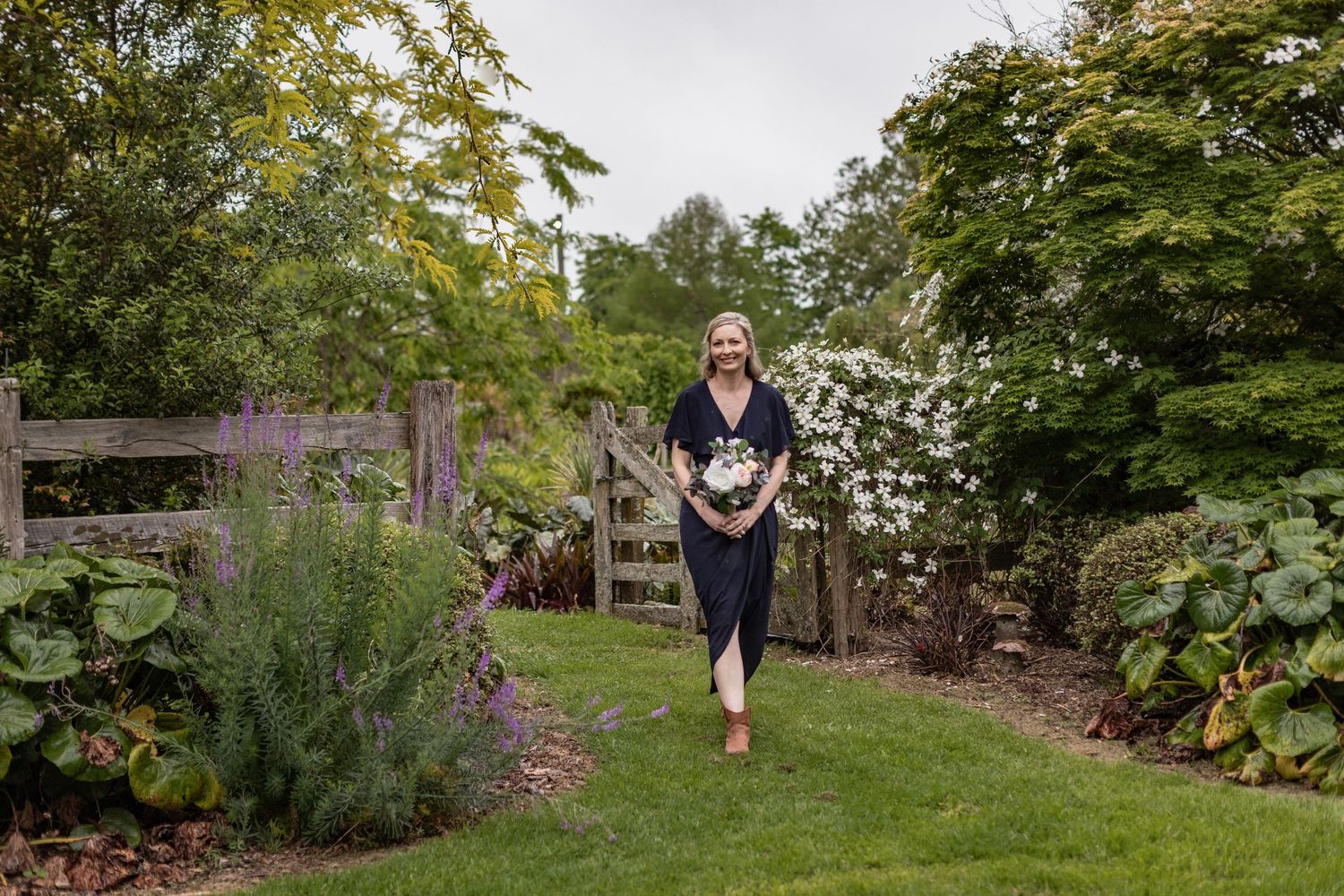 A scenic garden path winds through lush greenery and flowering plants on a sunny summer day.