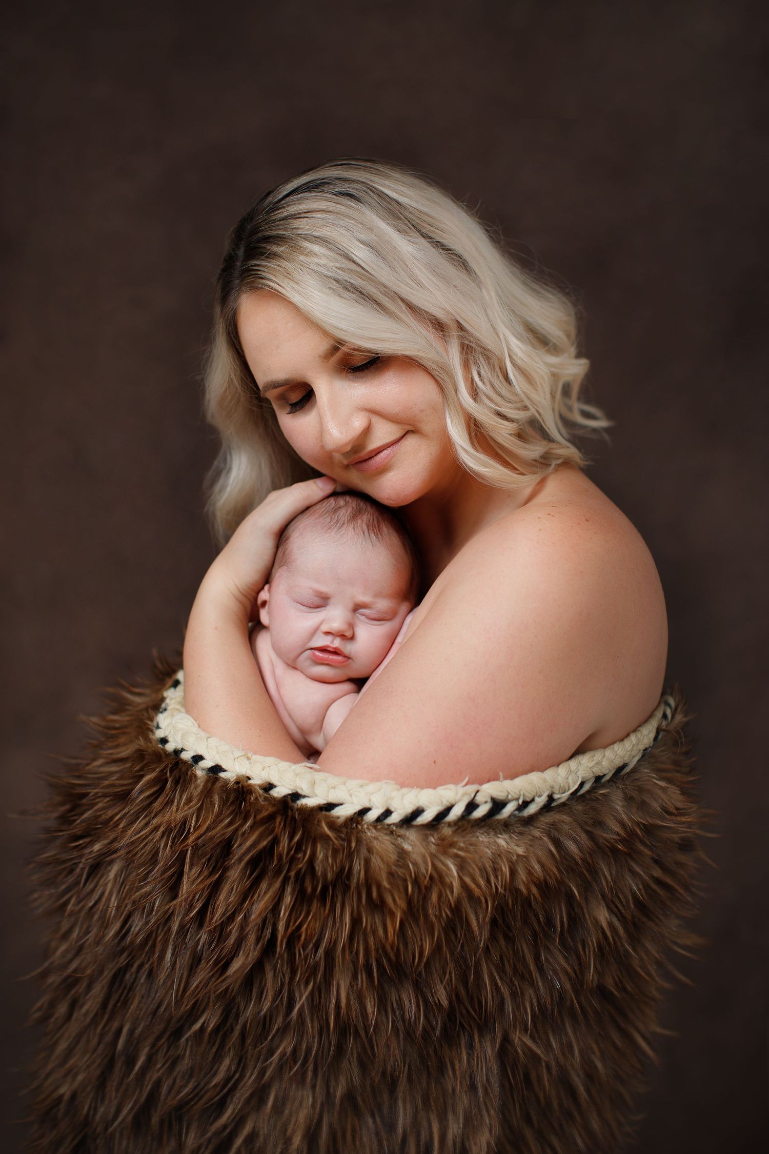 Tender moment captured in studio portrait with brown fur wrap and dark background. Cambridge Waikato NZ Photographer