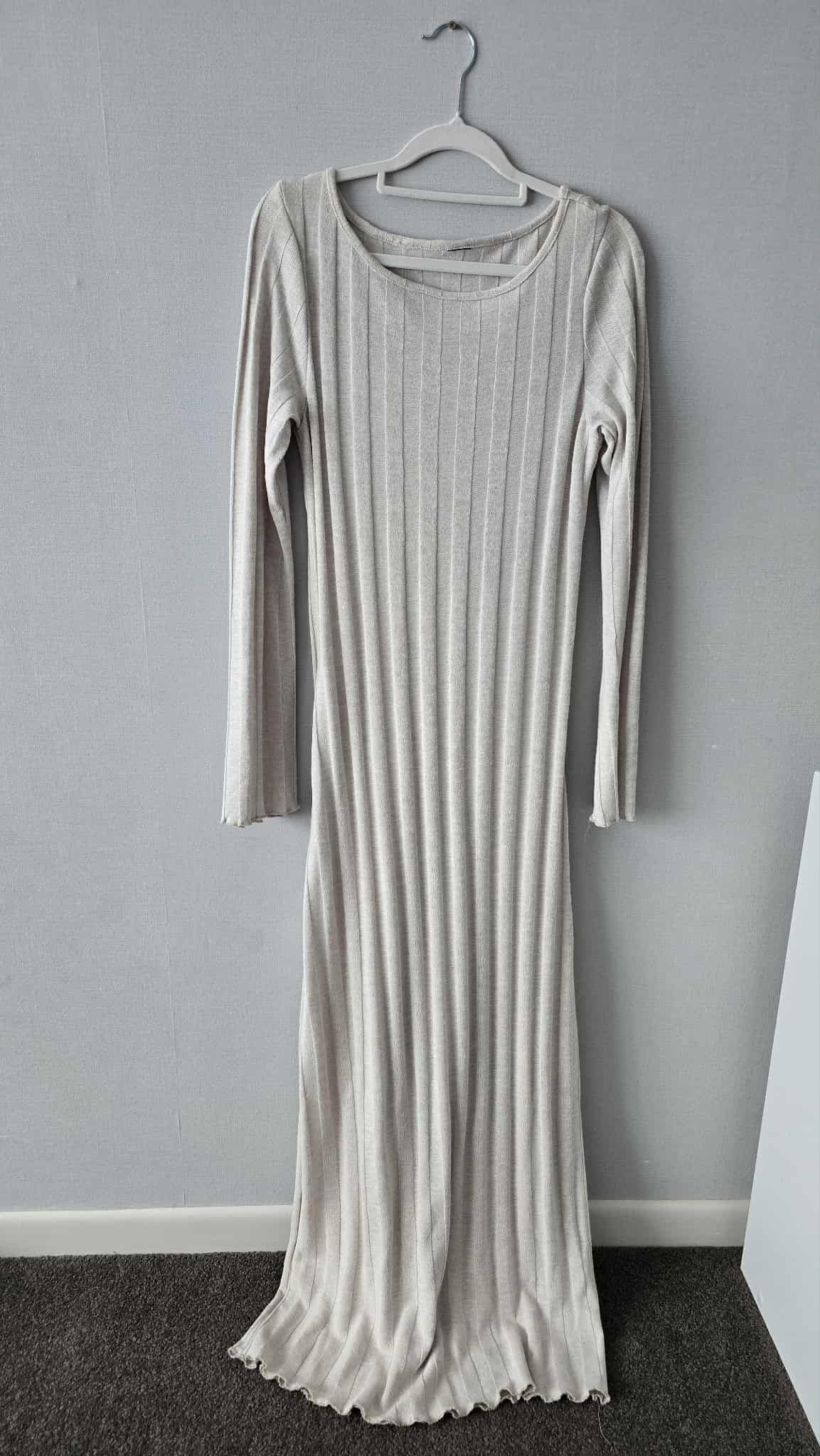 Light gray ribbed knit maxi dress with long sleeves and scoop neck, displayed on hanger against white wall.
